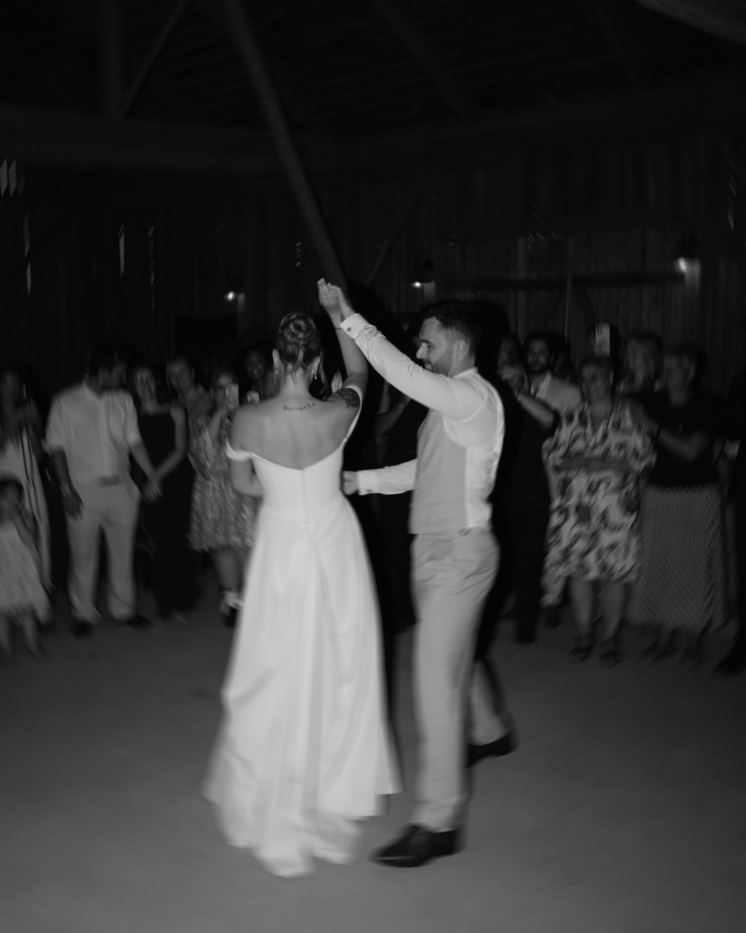 A couple dancing at a wedding reception in formal attire while guests watch from the dance floor perimeter.