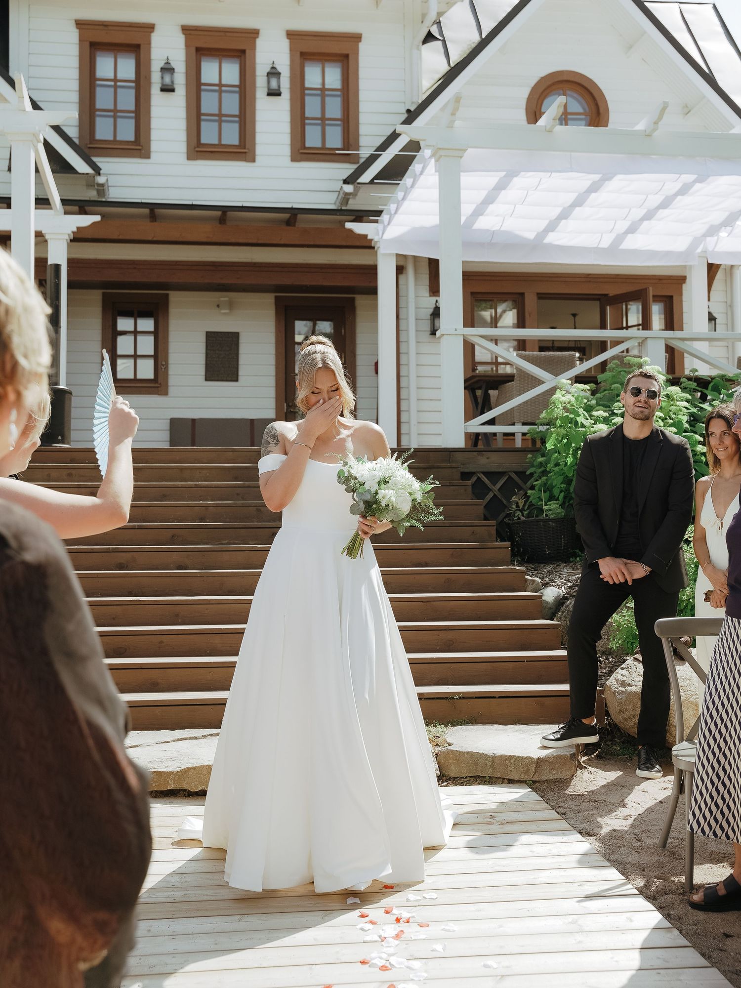 Elegant wedding ceremony held at beautiful white craftsman-style venue with wooden trim and grand staircase.