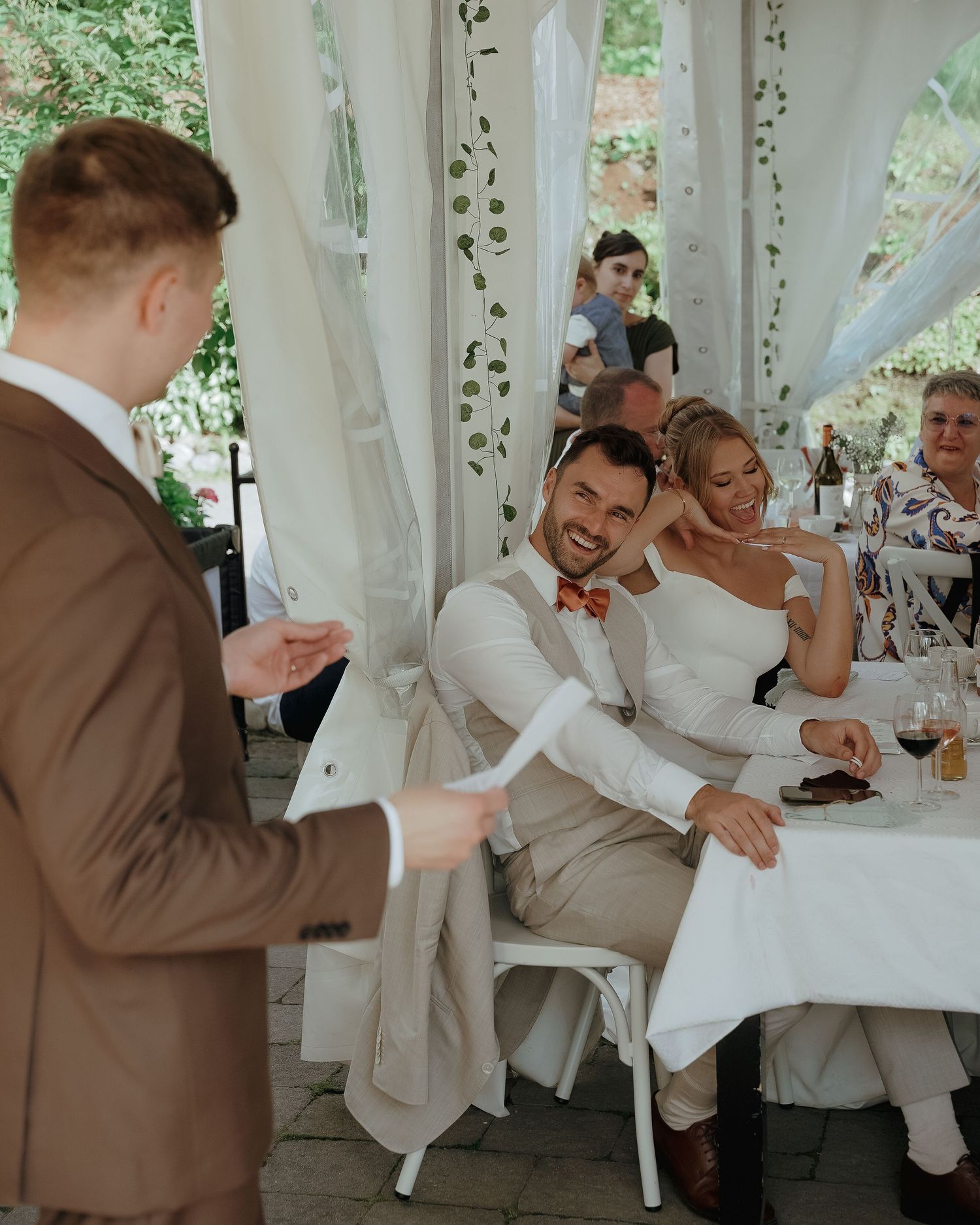 Wedding reception scene on an outdoor patio with white drapes and decorative vines creating an elegant atmosphere.