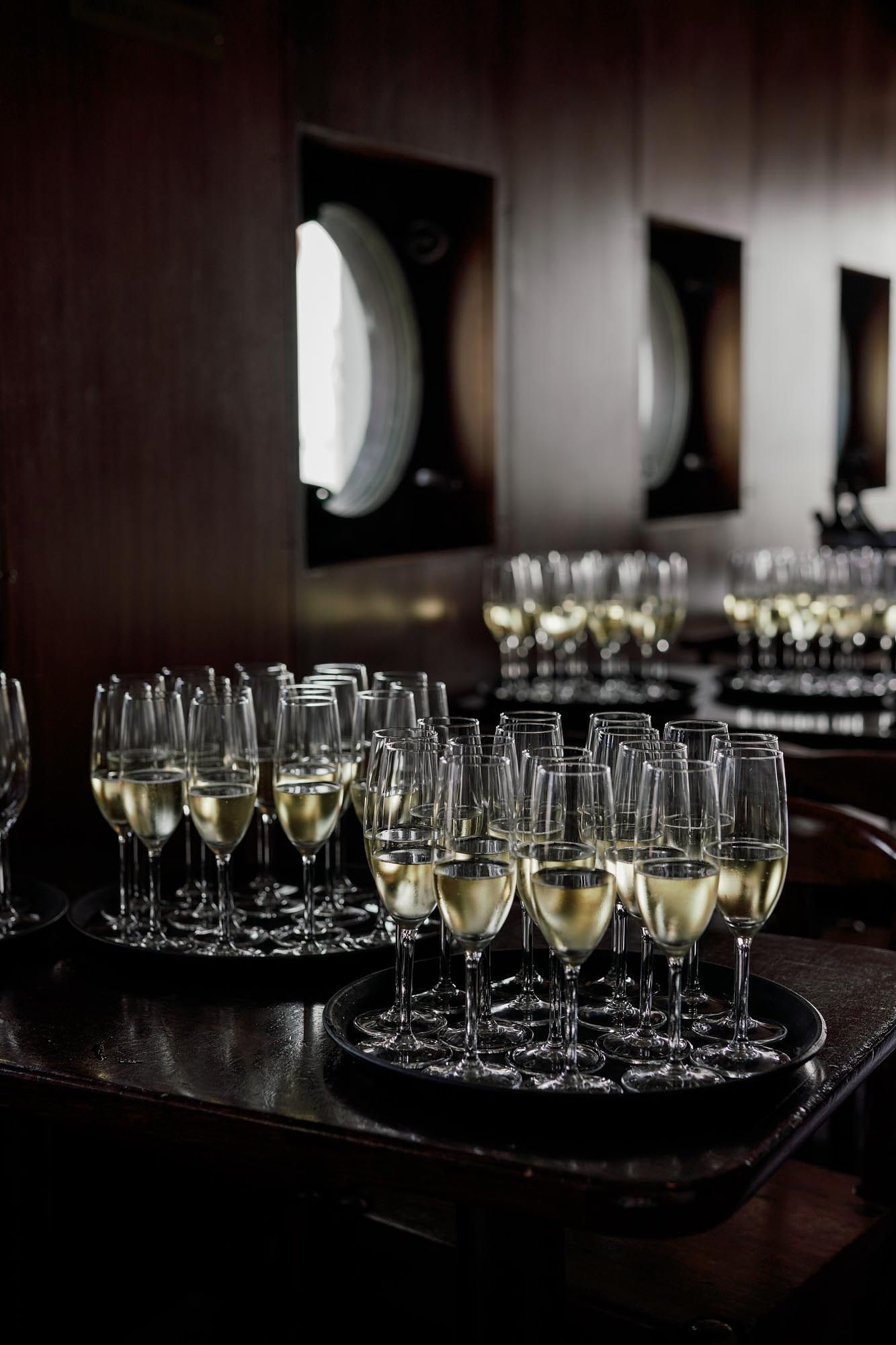 Elegant champagne flutes filled with sparkling wine arranged on trays in a dimly lit upscale venue.