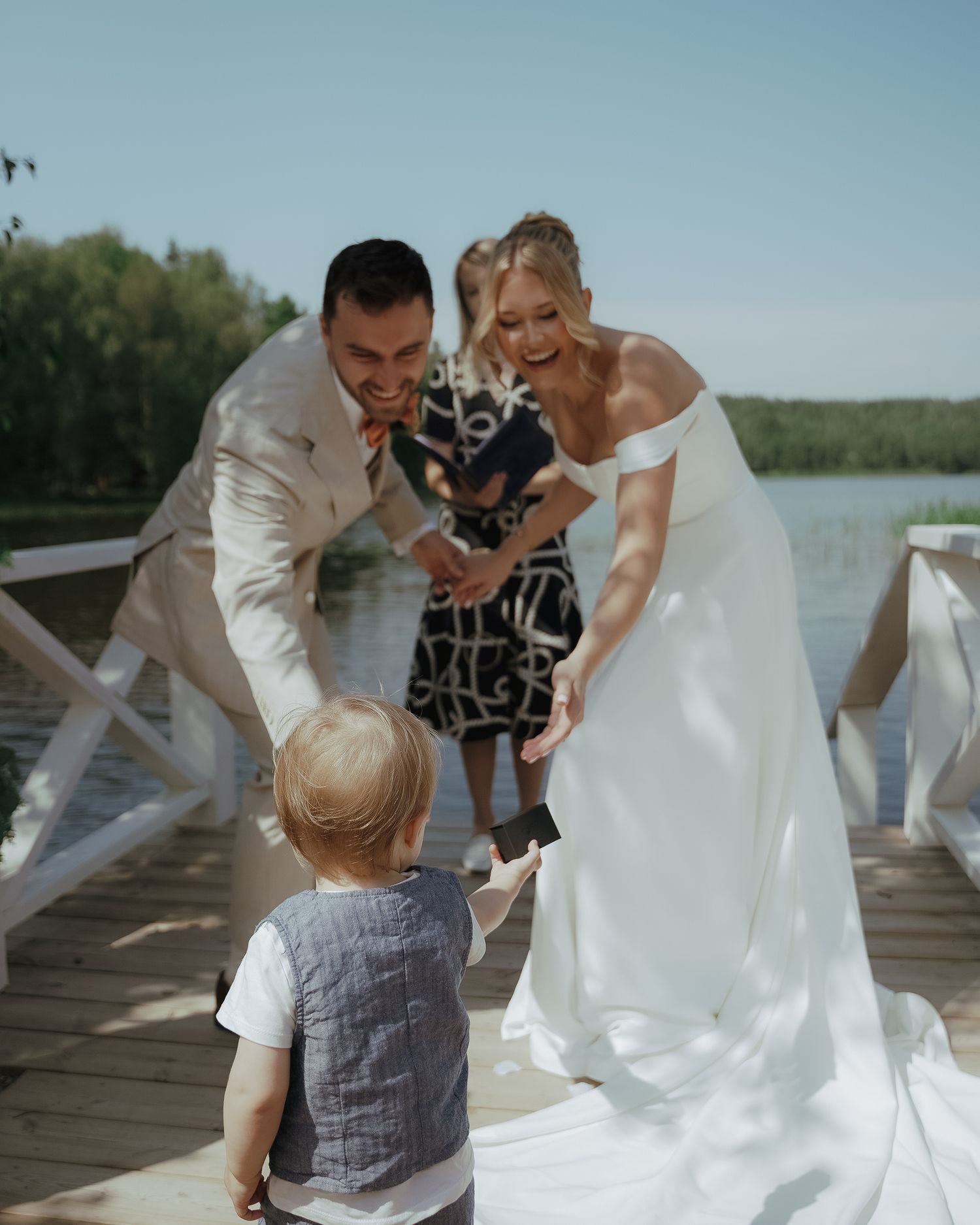 Series of candid wedding moments showing people in white attire joyfully interacting on a wooden deck by a lake.