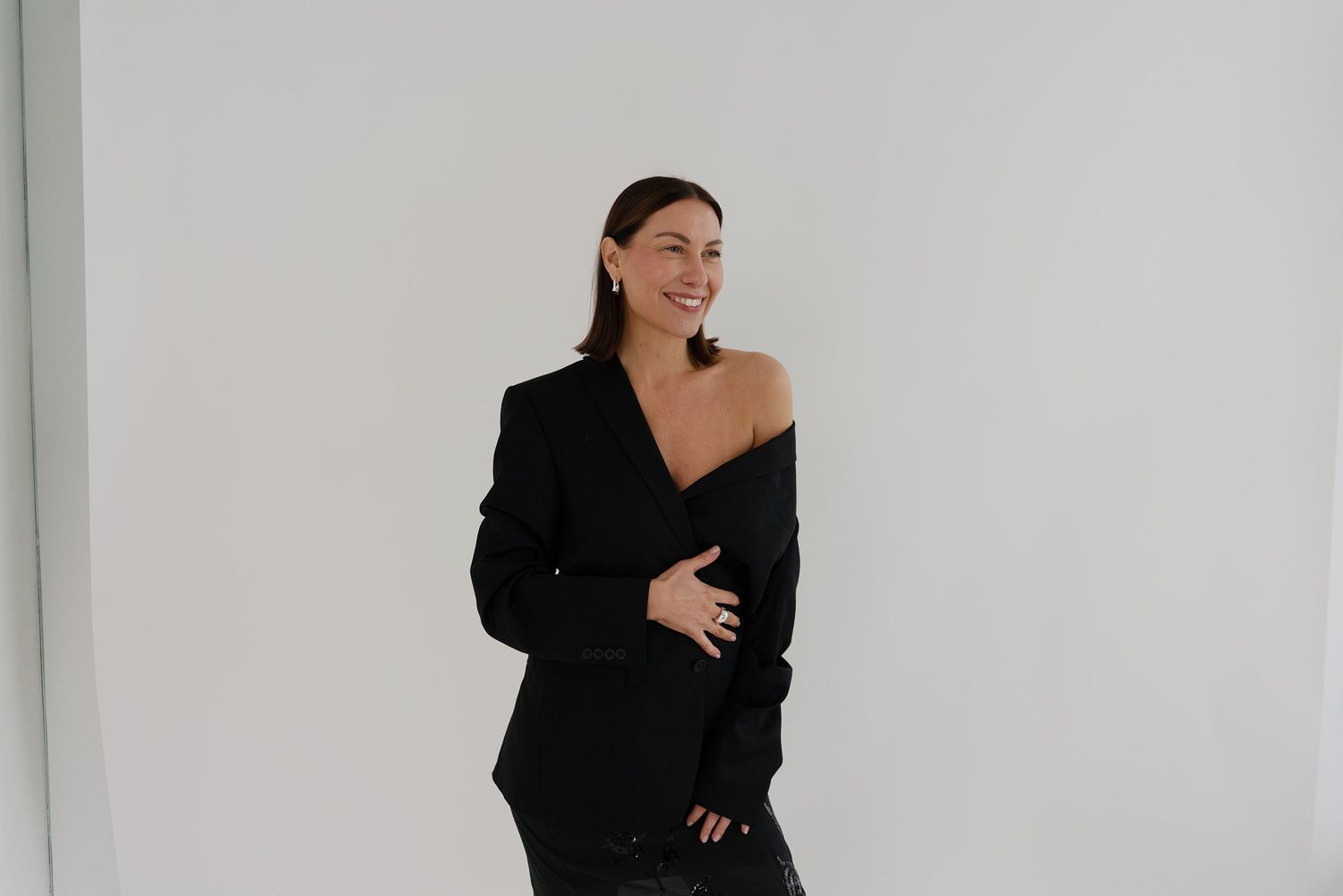 Fashion portrait in black blazer against minimalist white backdrop.