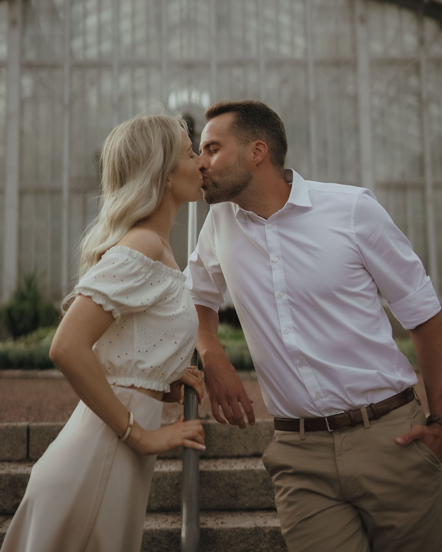 A tender romantic moment shared between a couple sitting on rustic outdoor steps at dusk.