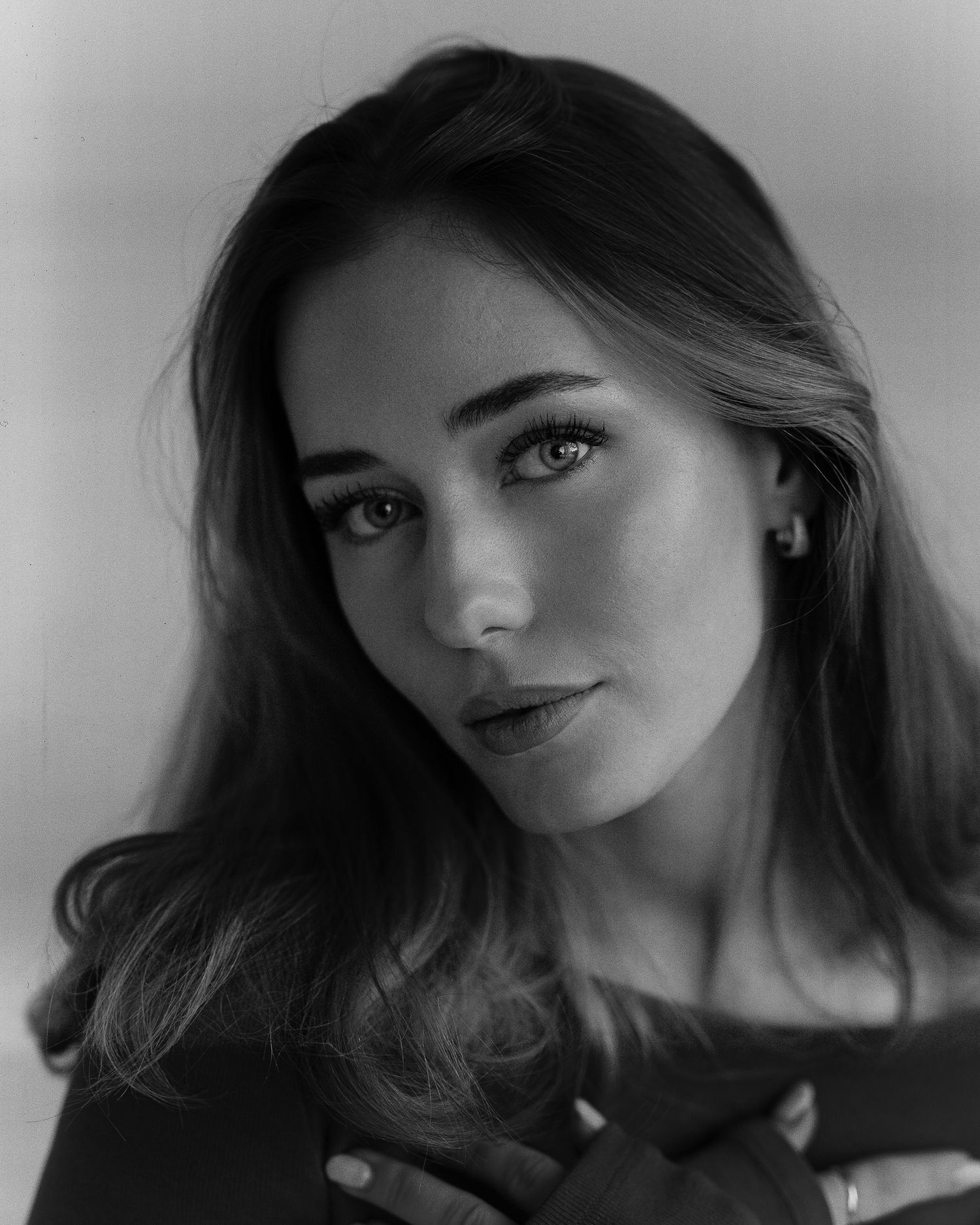 Black and white portrait photograph of a person with flowing hair and natural makeup looking to the side.