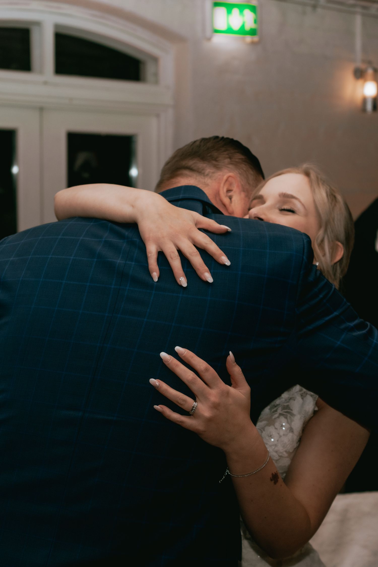 An intimate moment at a wedding reception as a couple embraces in a tender dance under soft lighting.