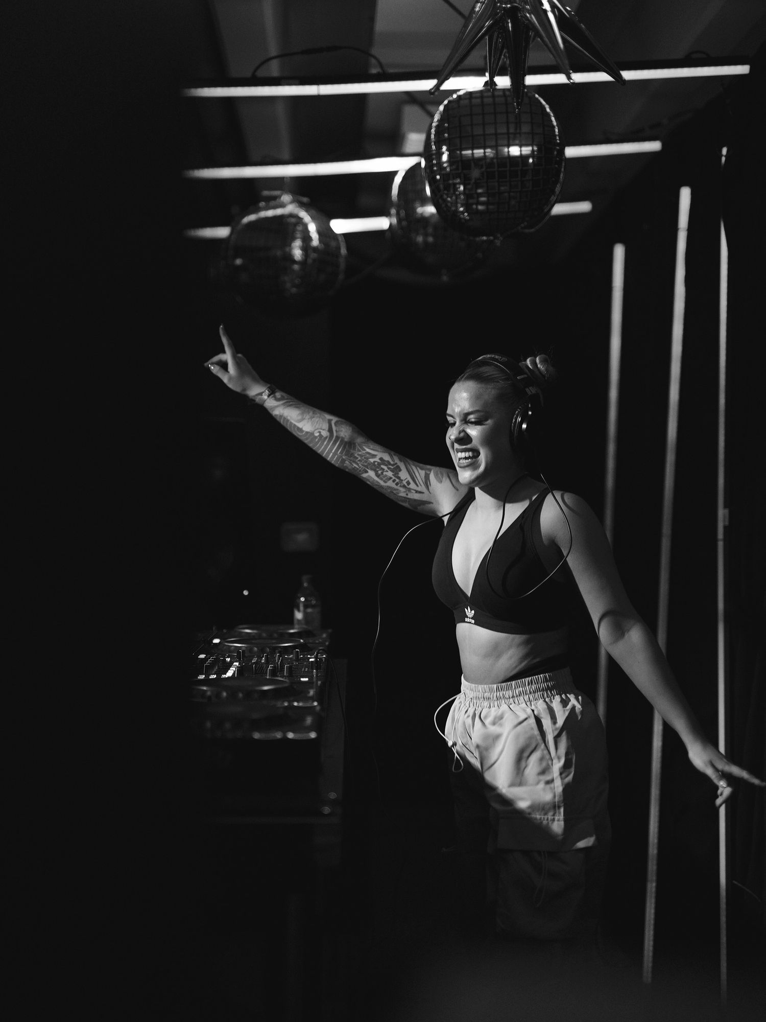 A person laughing during a performance wearing a black sports bra and light colored pants in dramatic black and white.
