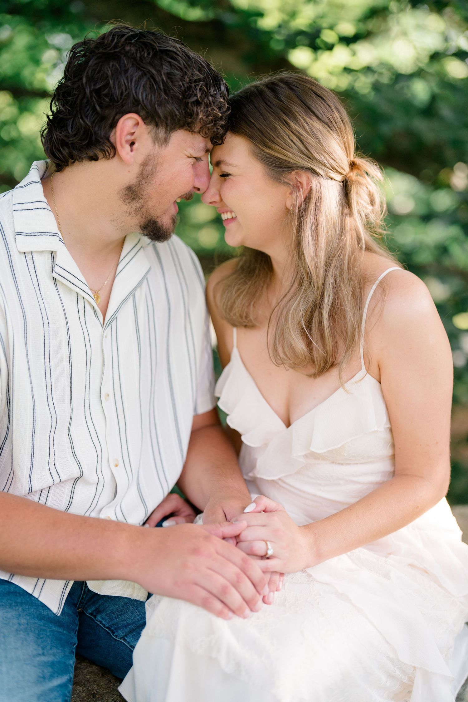 Couple sharing a romantic nose-to-nose moment, smiling and holding hands outdoors.