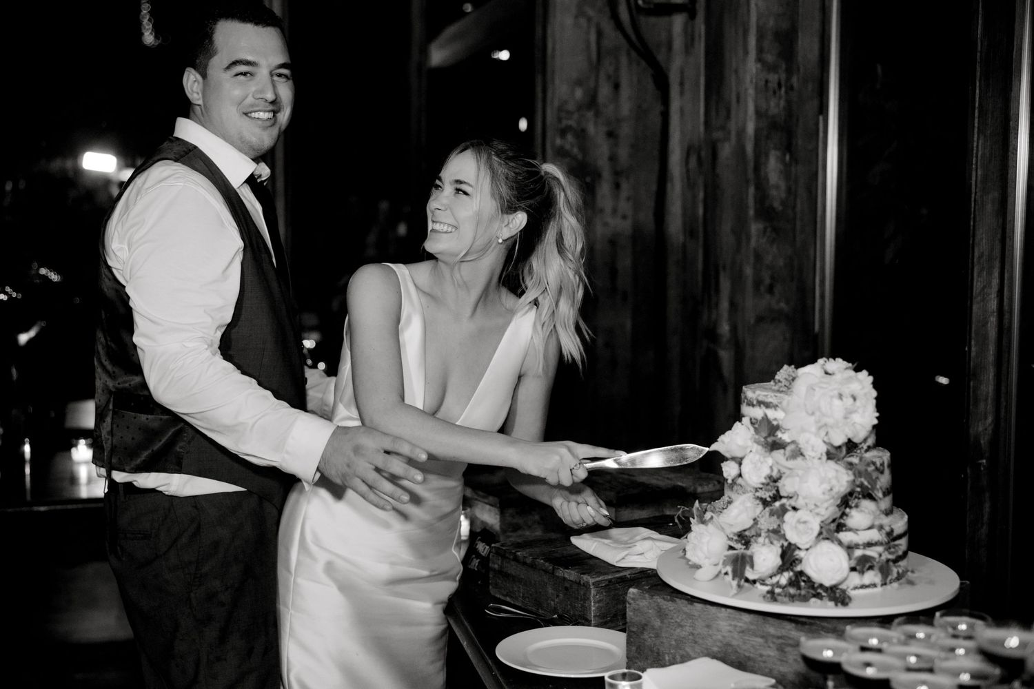 Couple sharing a joyful moment while cutting their wedding cake.