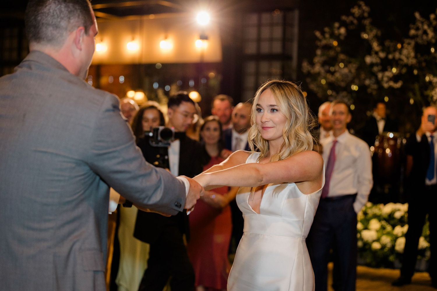 Couple dancing together at their wedding reception surrounded by guests.