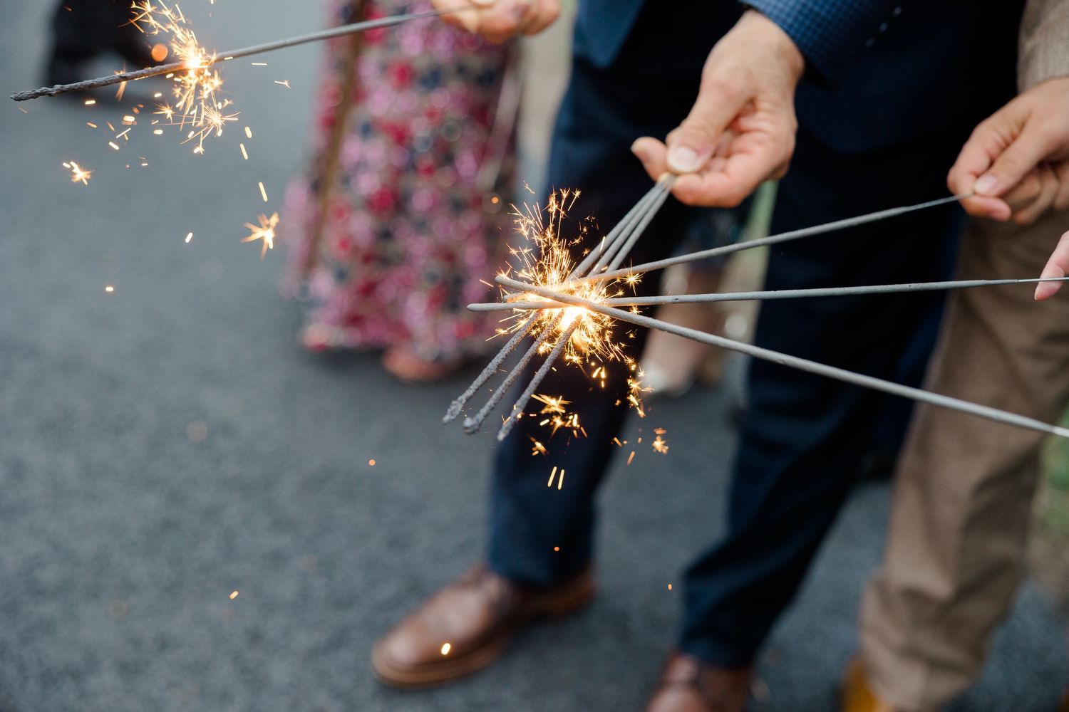 Close-up shot of lit sparklers creating bright sparks against a dark background.