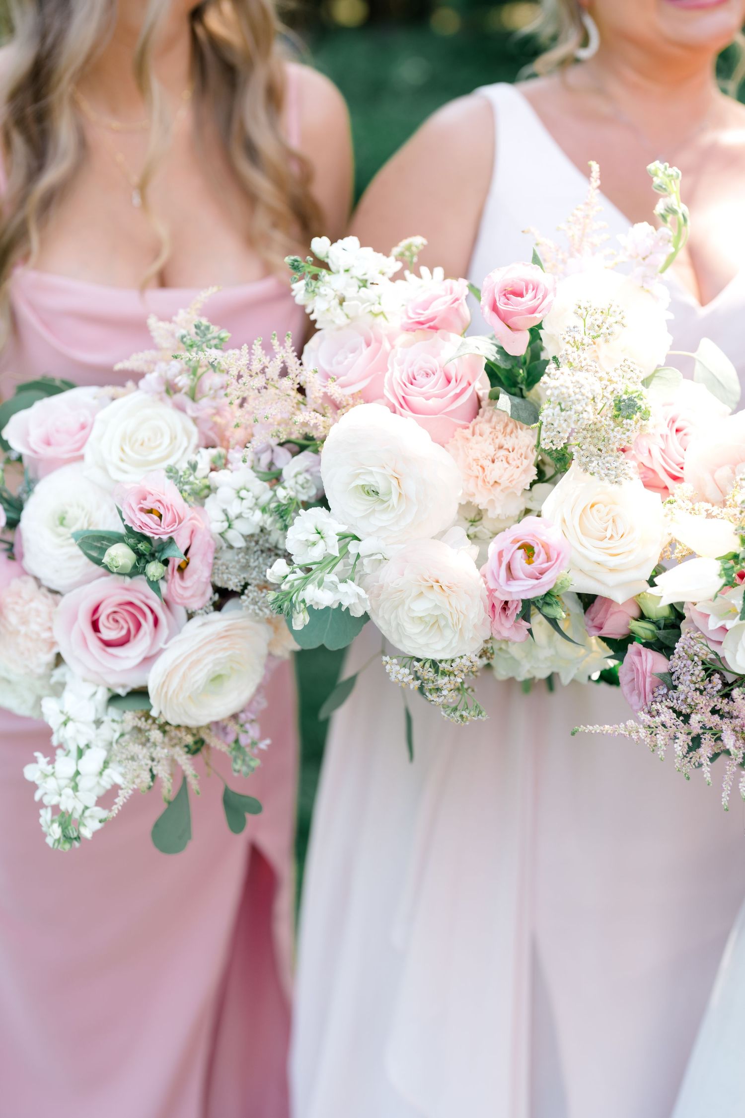 Elegant pink and white rose bouquets held against blush bridesmaid dresses.