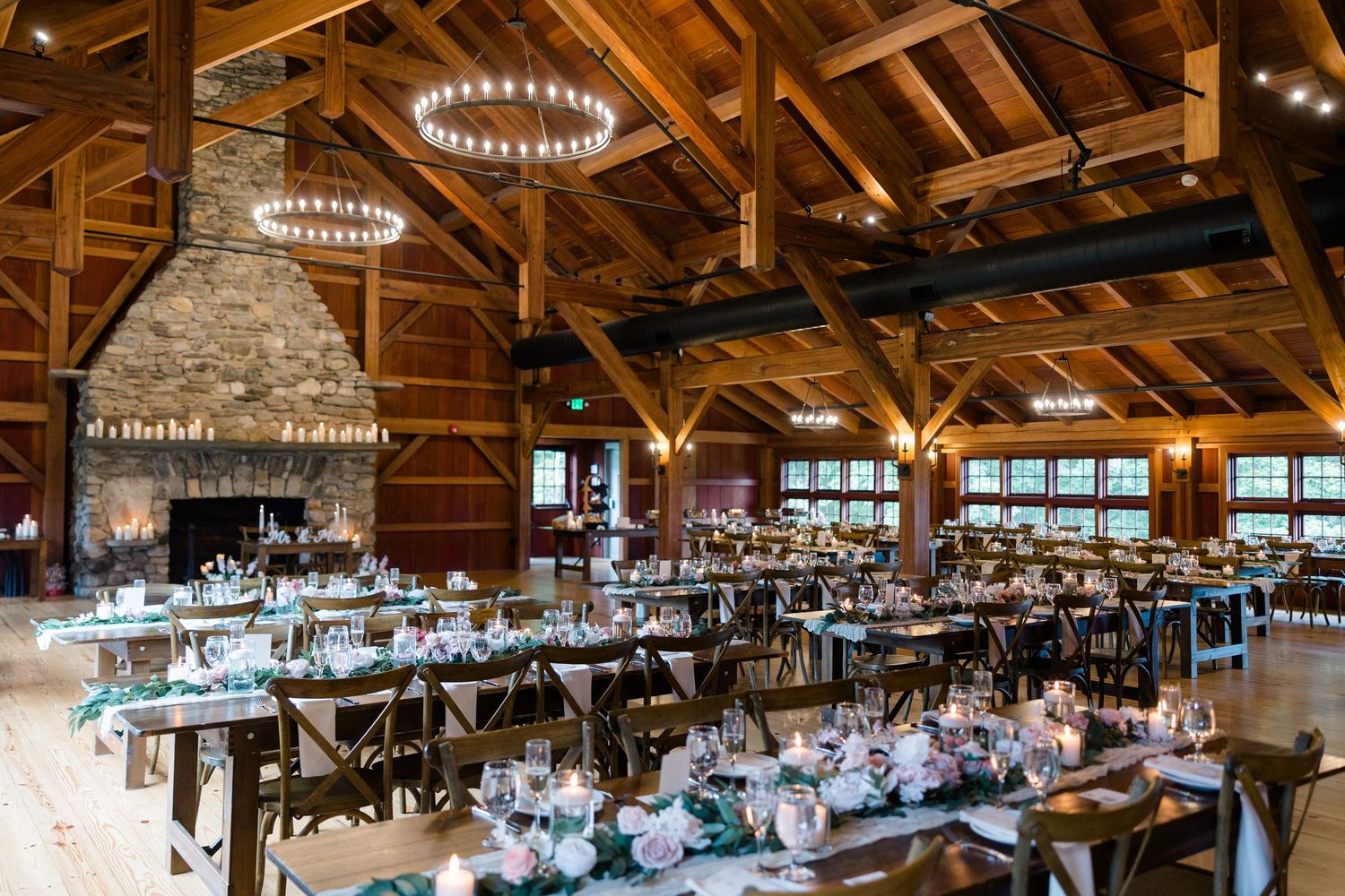 Rustic barn wedding reception venue with wooden beams and elegant chandeliers.