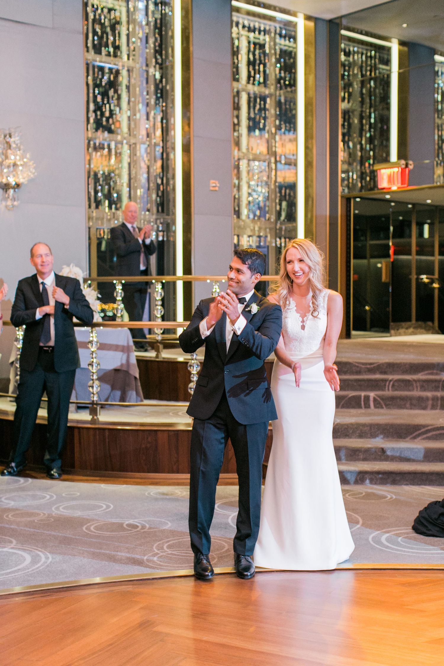 Wedding reception scene in luxurious venue with couple dancing on ornate floor.