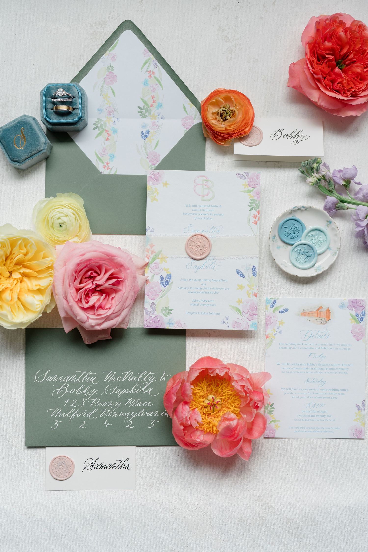 Elegant wedding invitation suite with floral design, sage green envelope, wax seals and colorful garden roses.