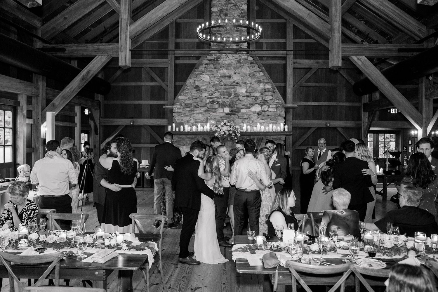 Rustic barn wedding reception venue with exposed wooden beams and stone fireplace.