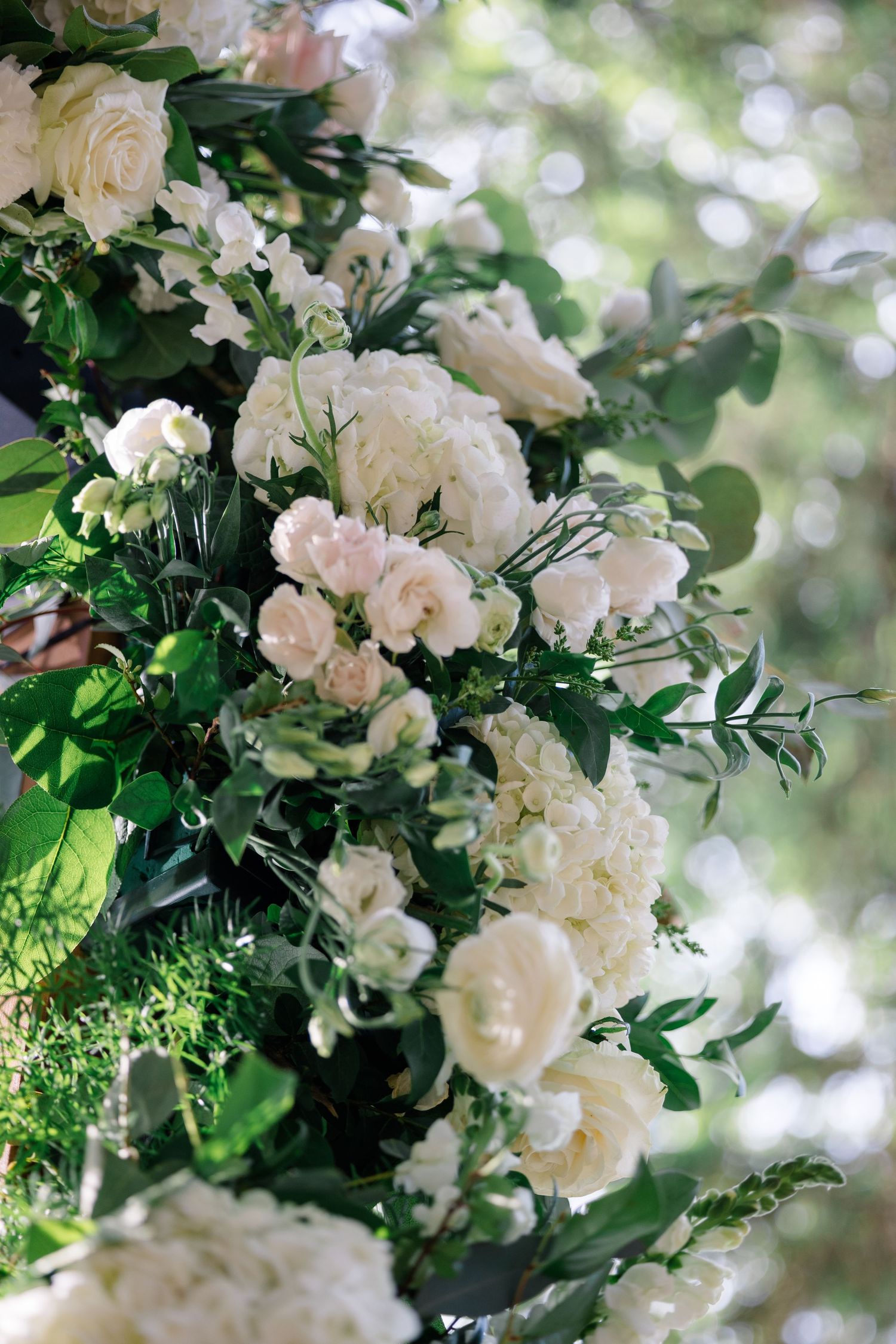 Romantic white and blush floral arrangement with roses and greenery in soft natural lighting.
