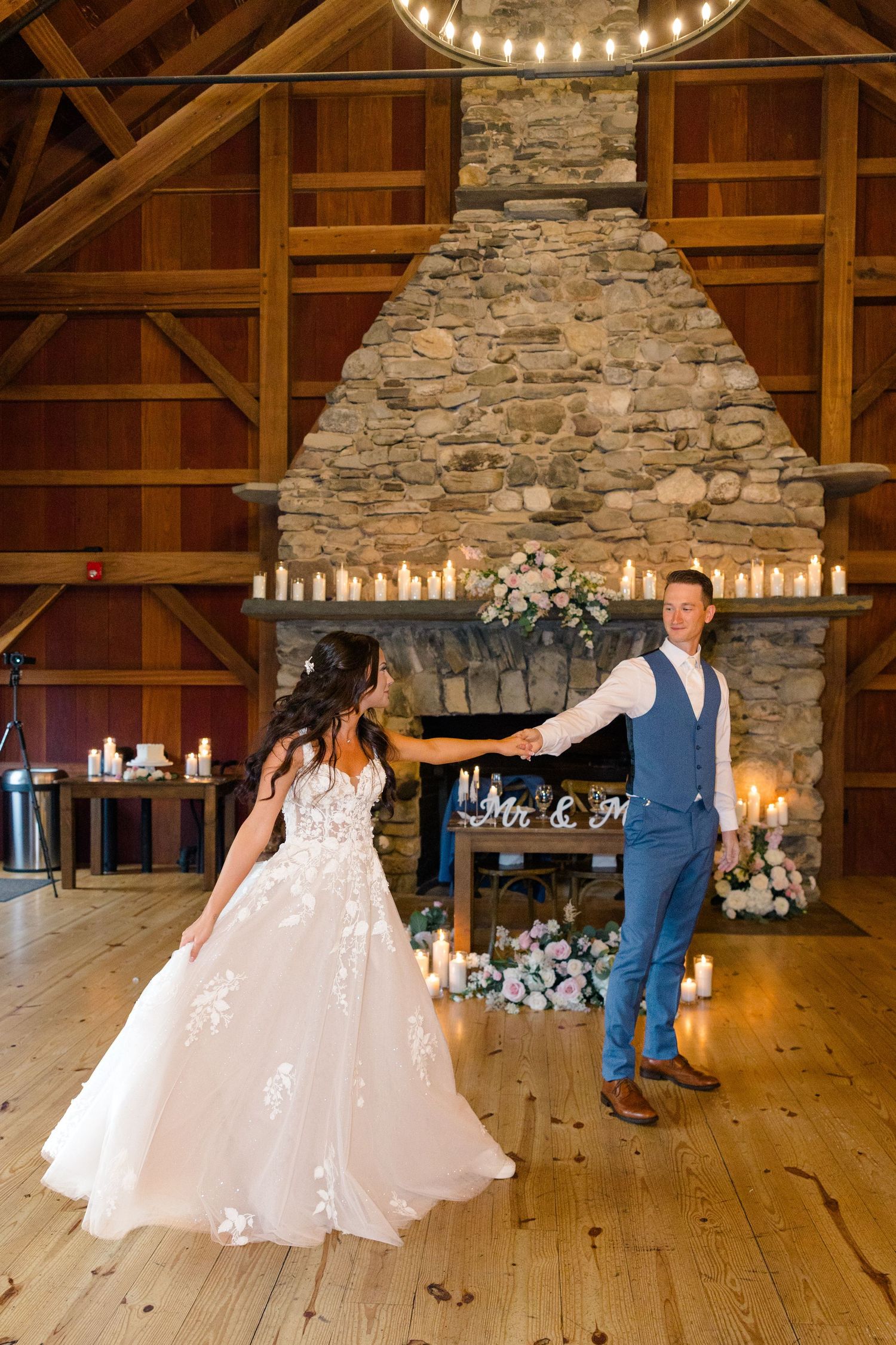 Rustic barn venue with stone fireplace and wooden floors set up for an elegant wedding celebration.