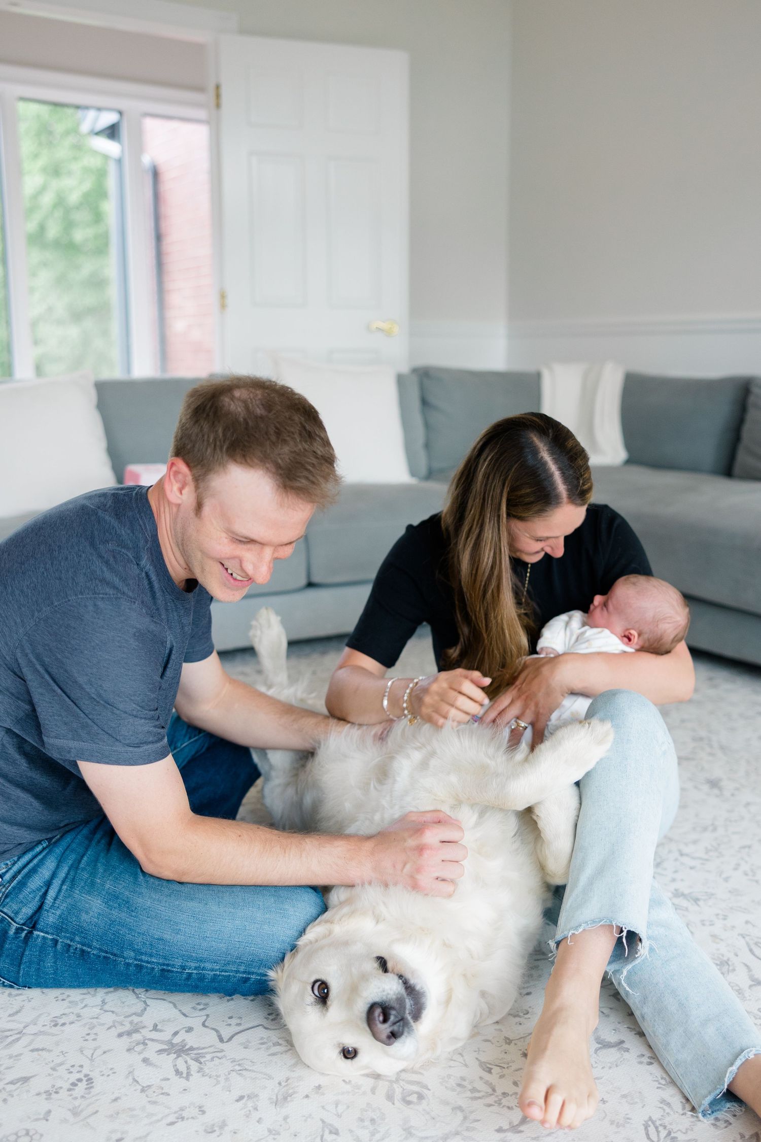 A family and their happy Golden Retriever share a tender moment together on a grey carpet.
