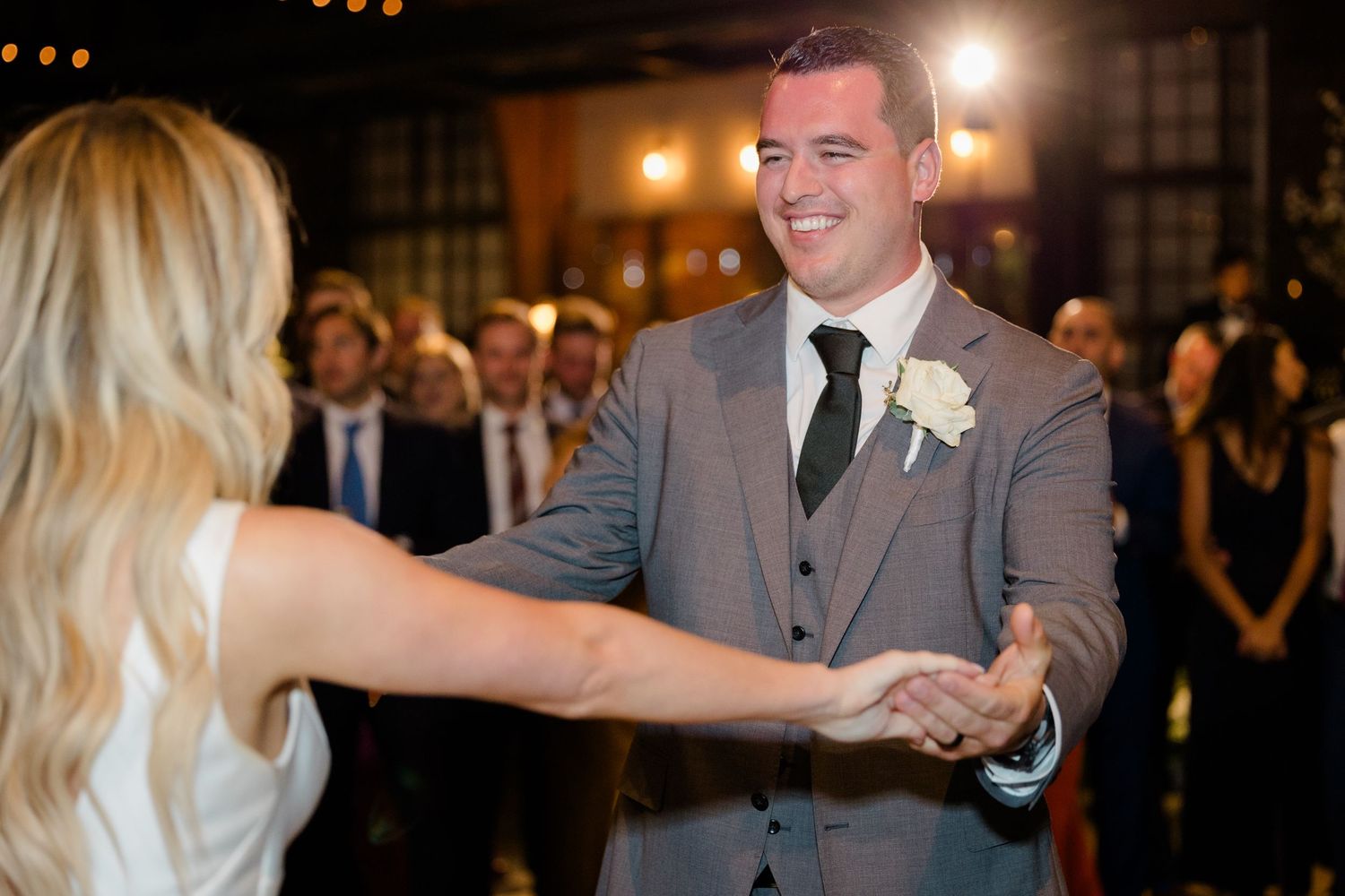 A romantic first dance moment between newlyweds at a warmly lit indoor wedding reception venue.
