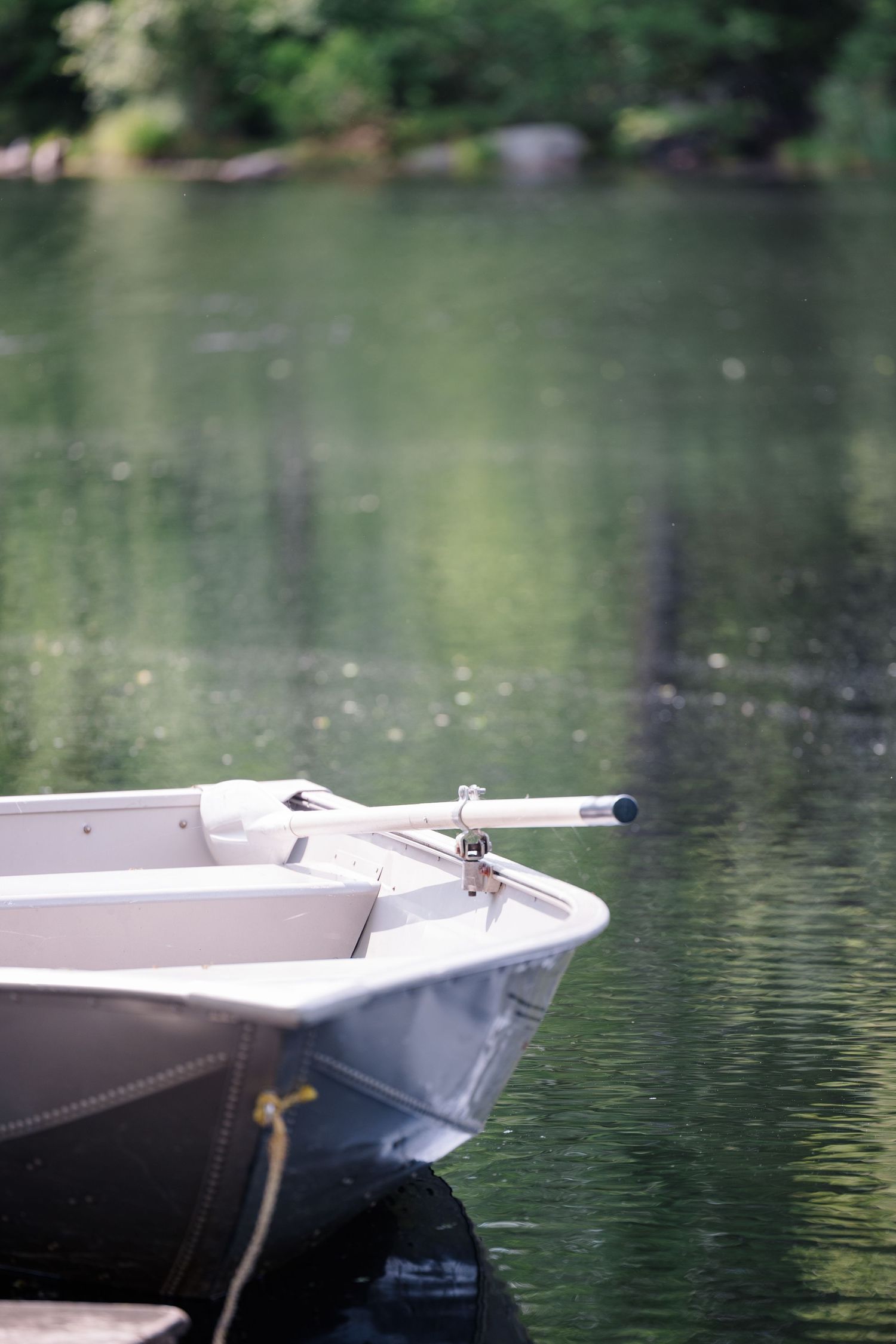 White rowboat bow floating on calm lake waters with peaceful reflections.
