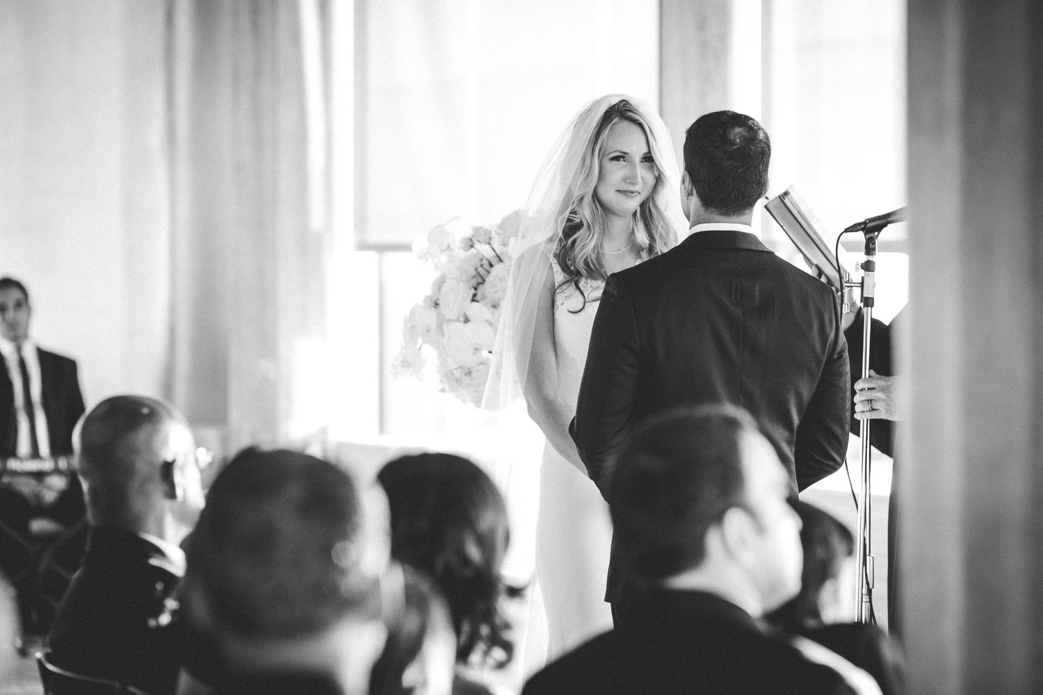 Black and white wedding ceremony photo capturing bride and groom at the altar.