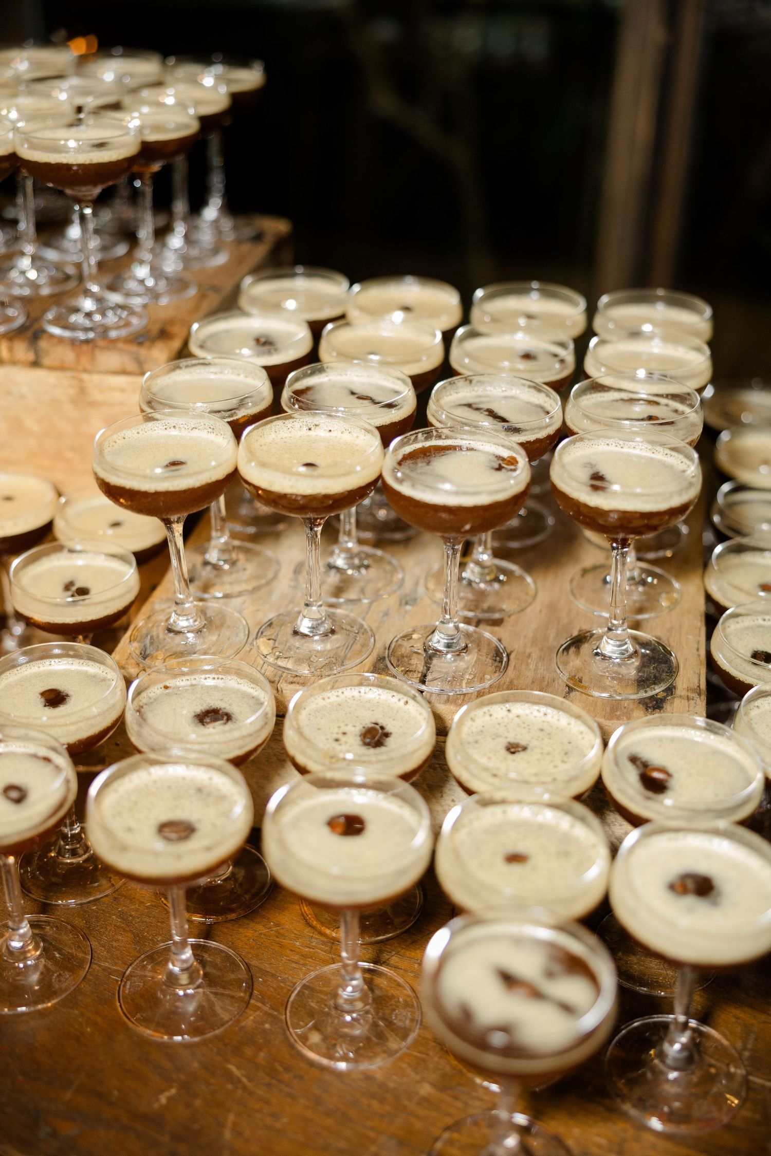 Rows of champagne cocktails lined up on a wooden table at an elegant event.