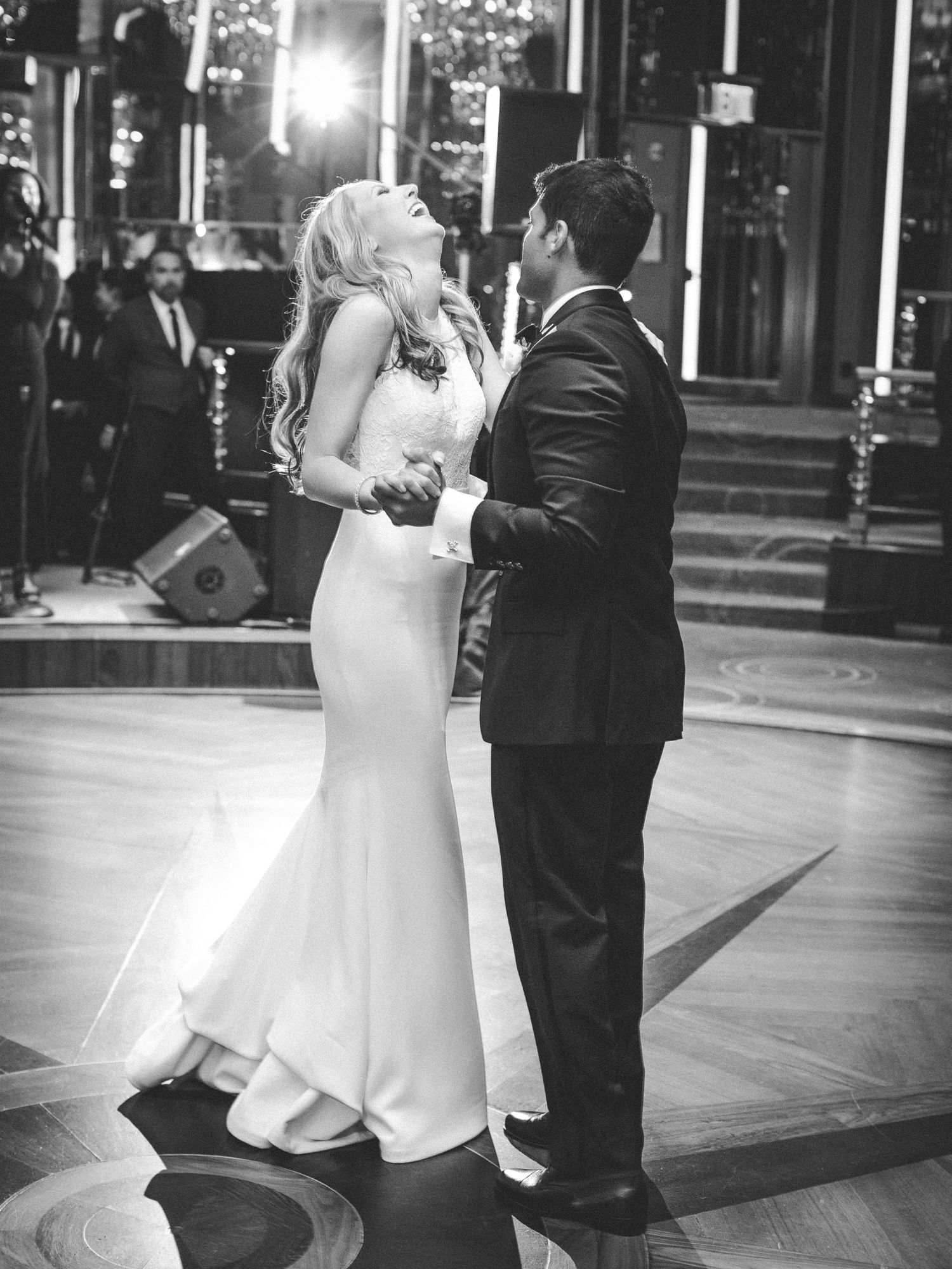 Black and white photograph of a couple sharing a romantic moment during their first dance at a reception.