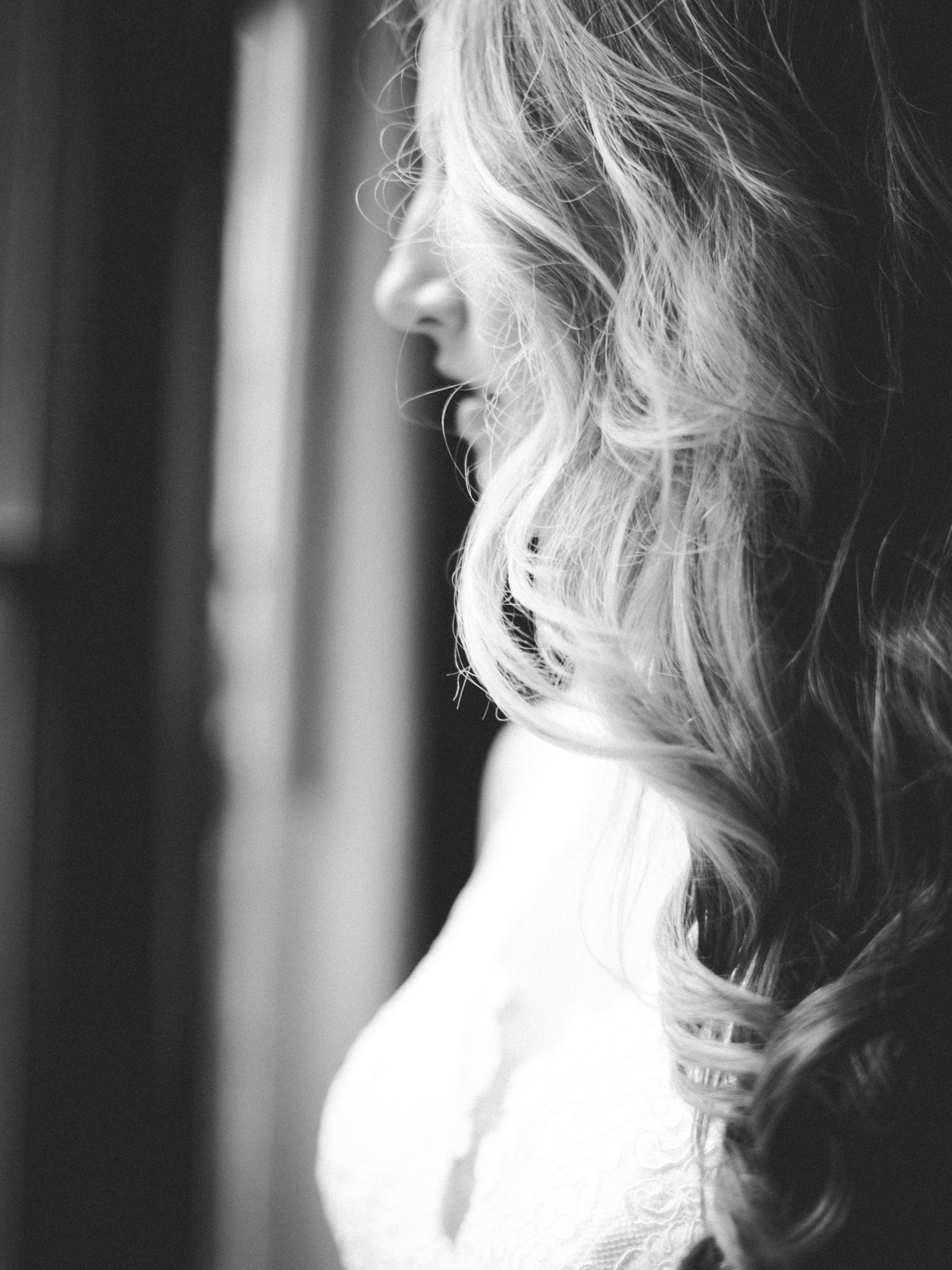 Black and white profile portrait of flowing blonde hair against a window with natural light.
