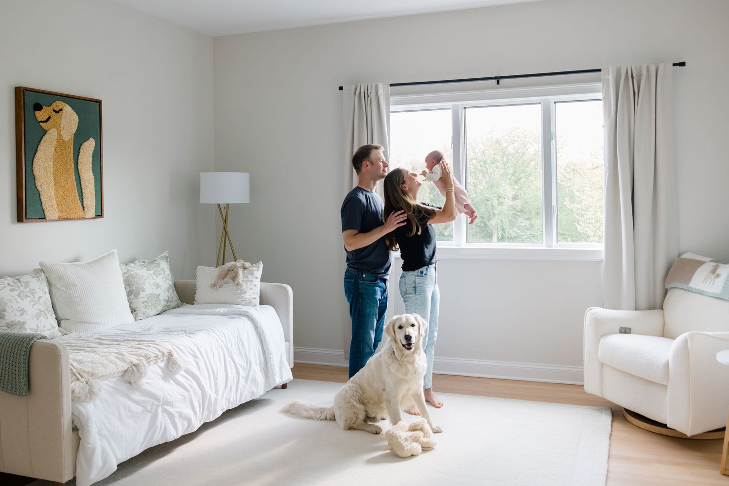 A couple dances together in a bright living room with white furniture and a Golden Retriever sitting nearby.