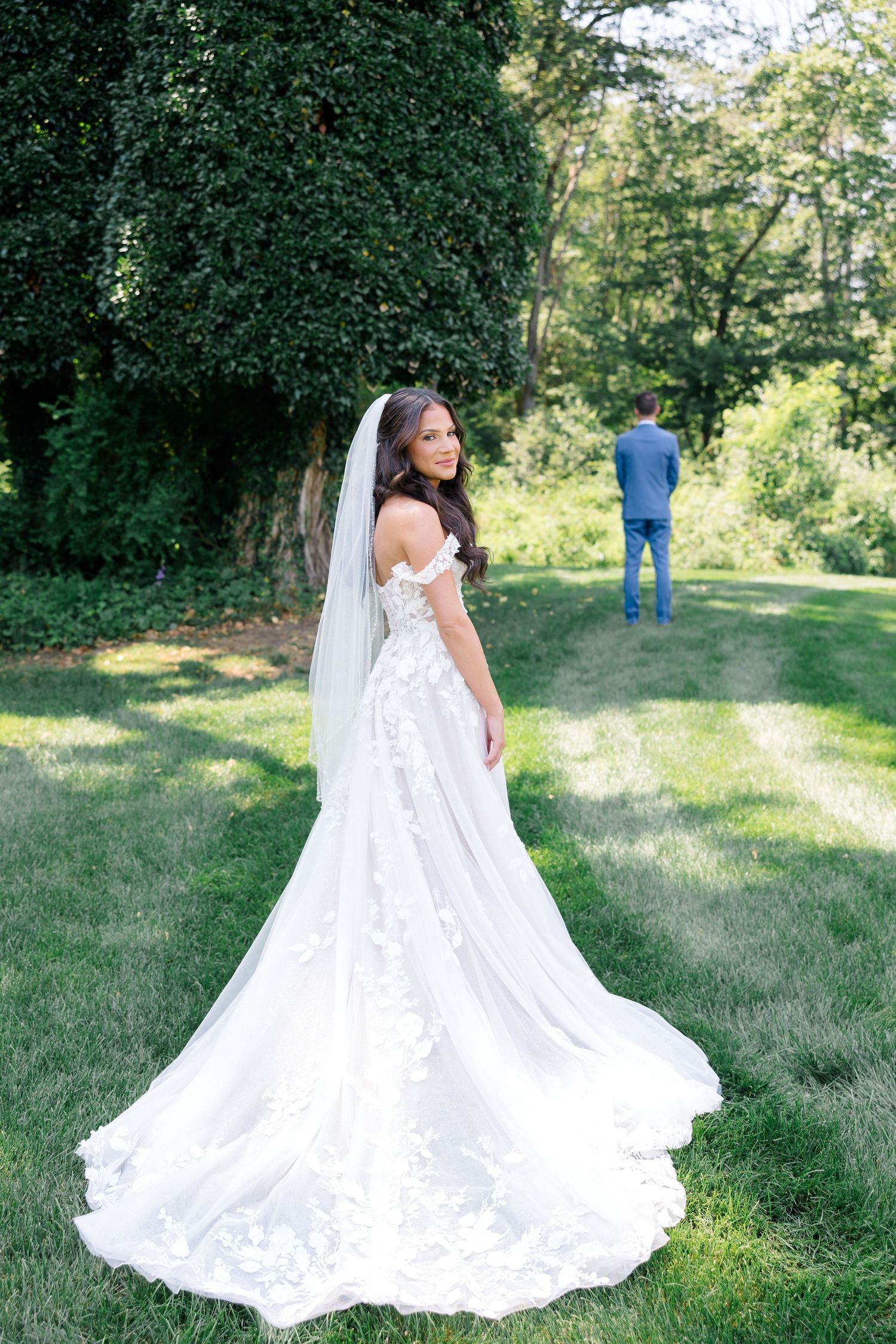 Beautiful flowy white lace wedding dress with cathedral train displayed in outdoor garden setting.