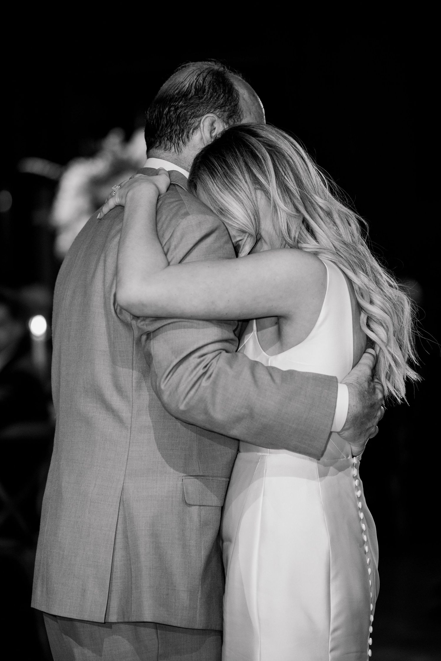 Intimate black and white photo of a couple embracing during their wedding dance.