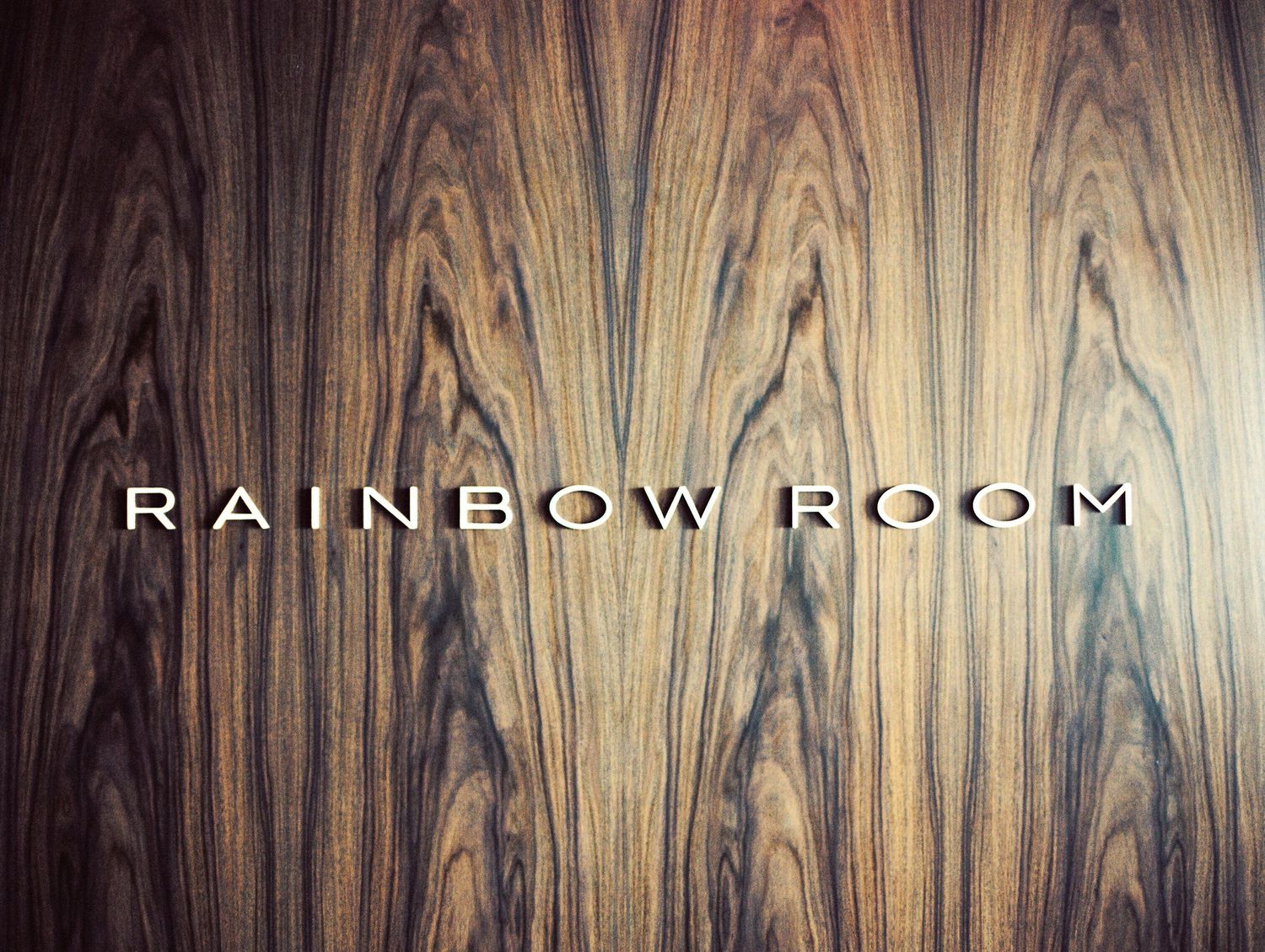 Rainbow Room text on wood grain panel wall with dramatic lighting.