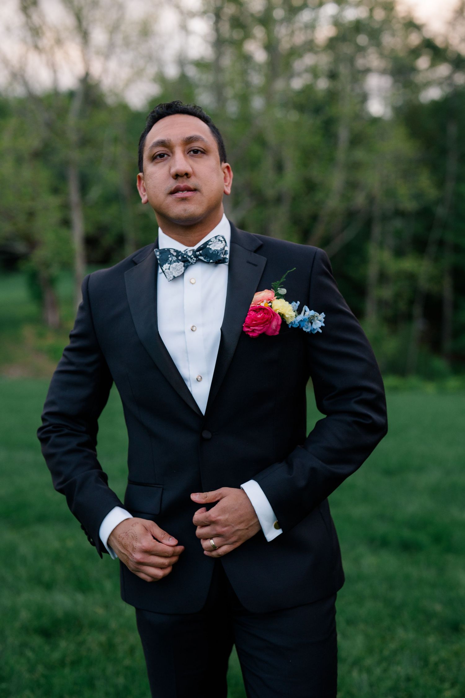 Portrait of a formal attired person wearing a black tuxedo with bow tie and floral boutonniere.