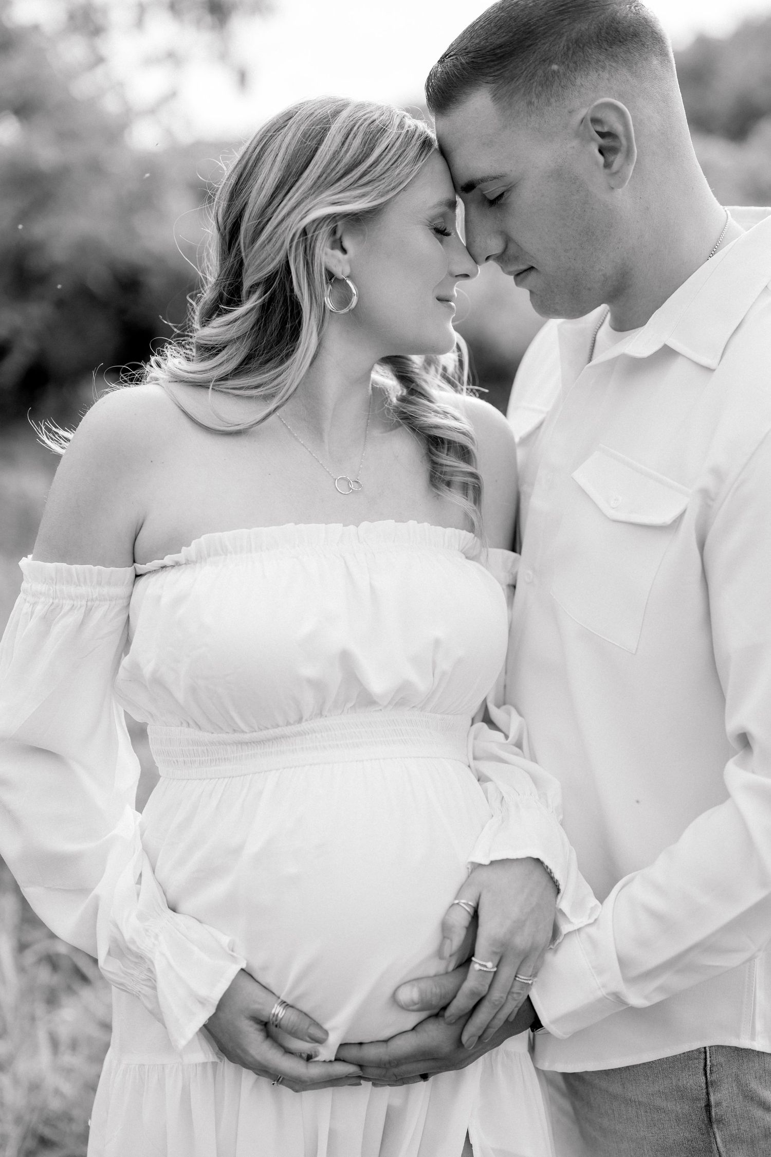 Intimate black and white maternity portrait showing tender moment between couple.