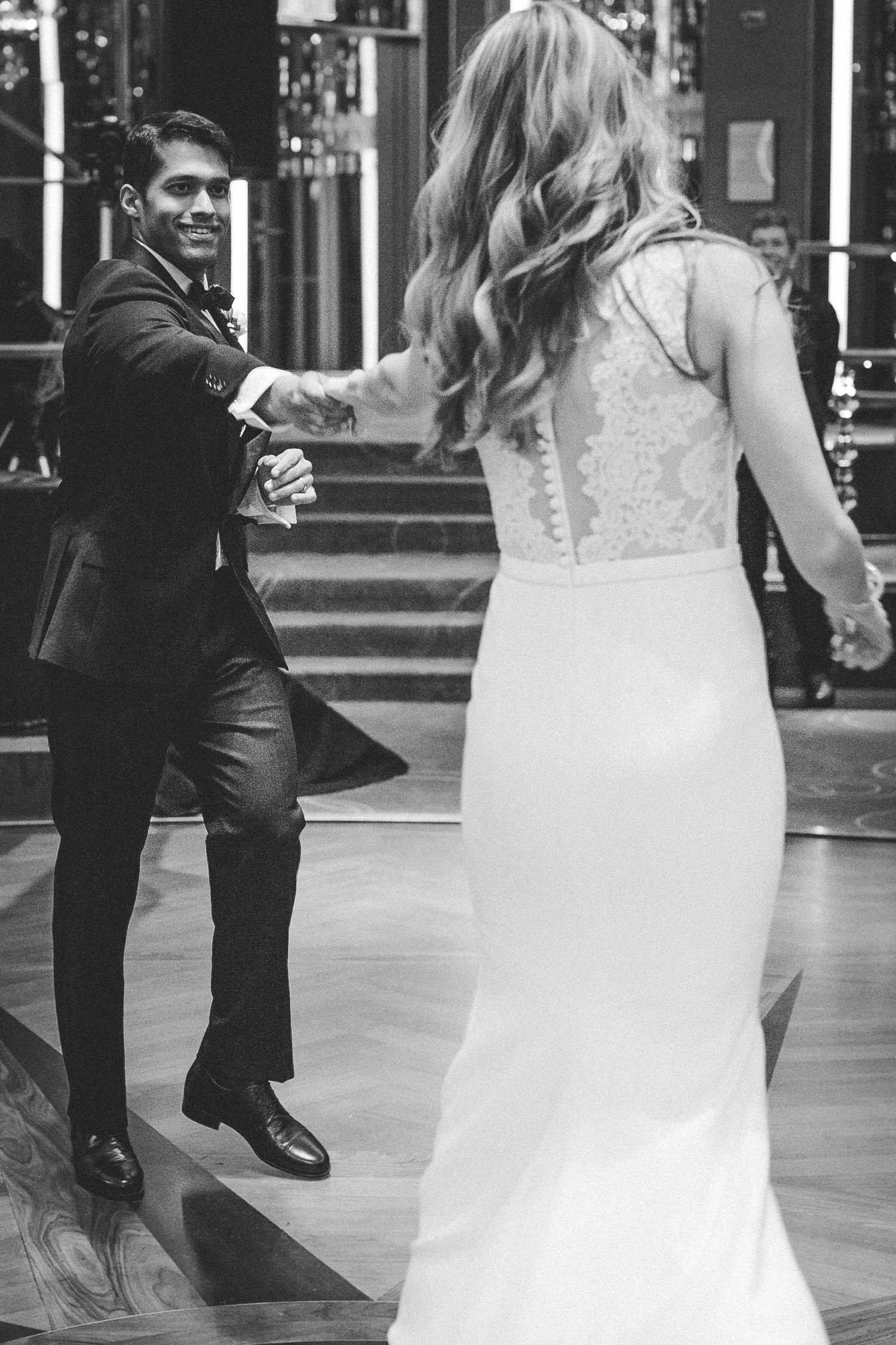 A couple shares their first dance at a wedding celebration, with the bride wearing a fitted lace gown.