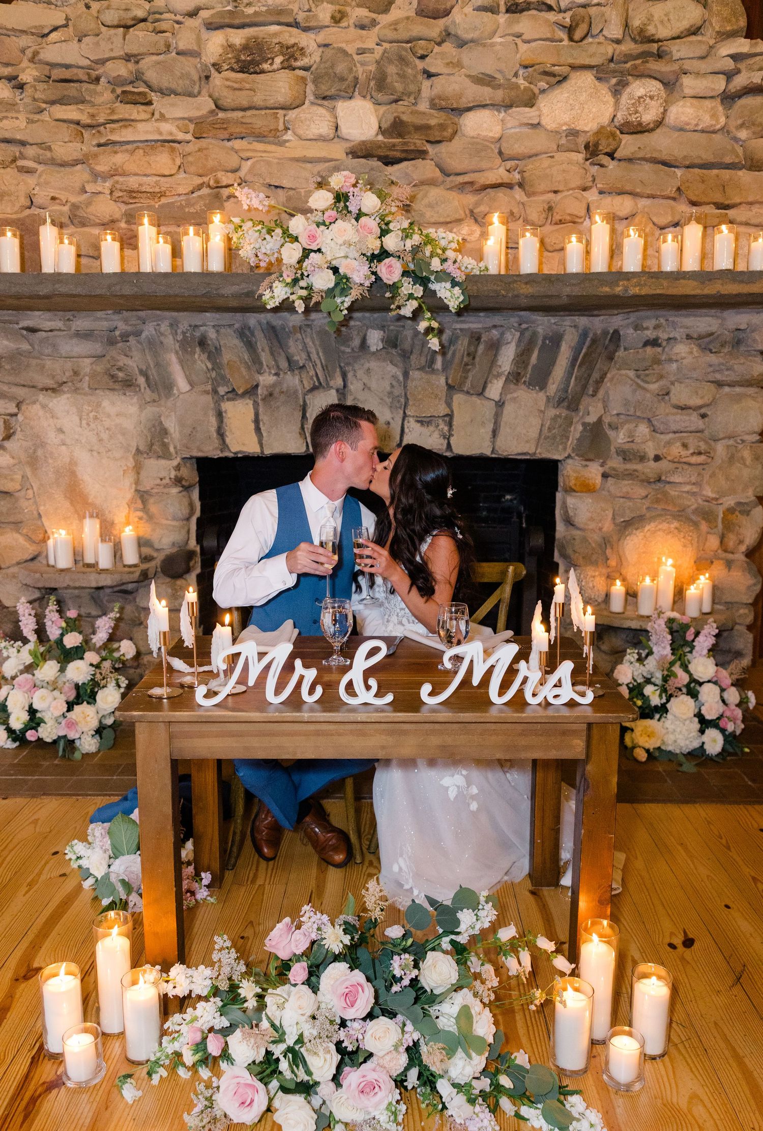 Romantic wedding reception decor with stone walls, glowing candles, and pink floral arrangements.