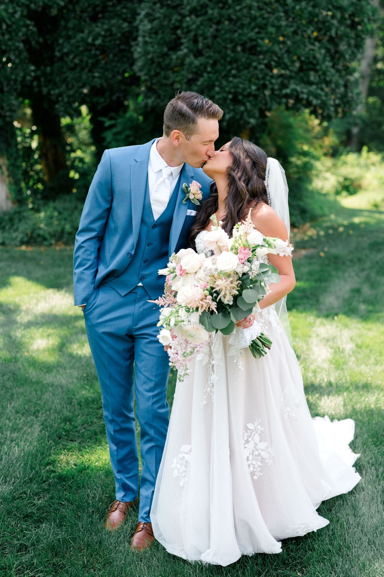 A couple shares a romantic moment in wedding attire with the bride in white and groom in blue suit.