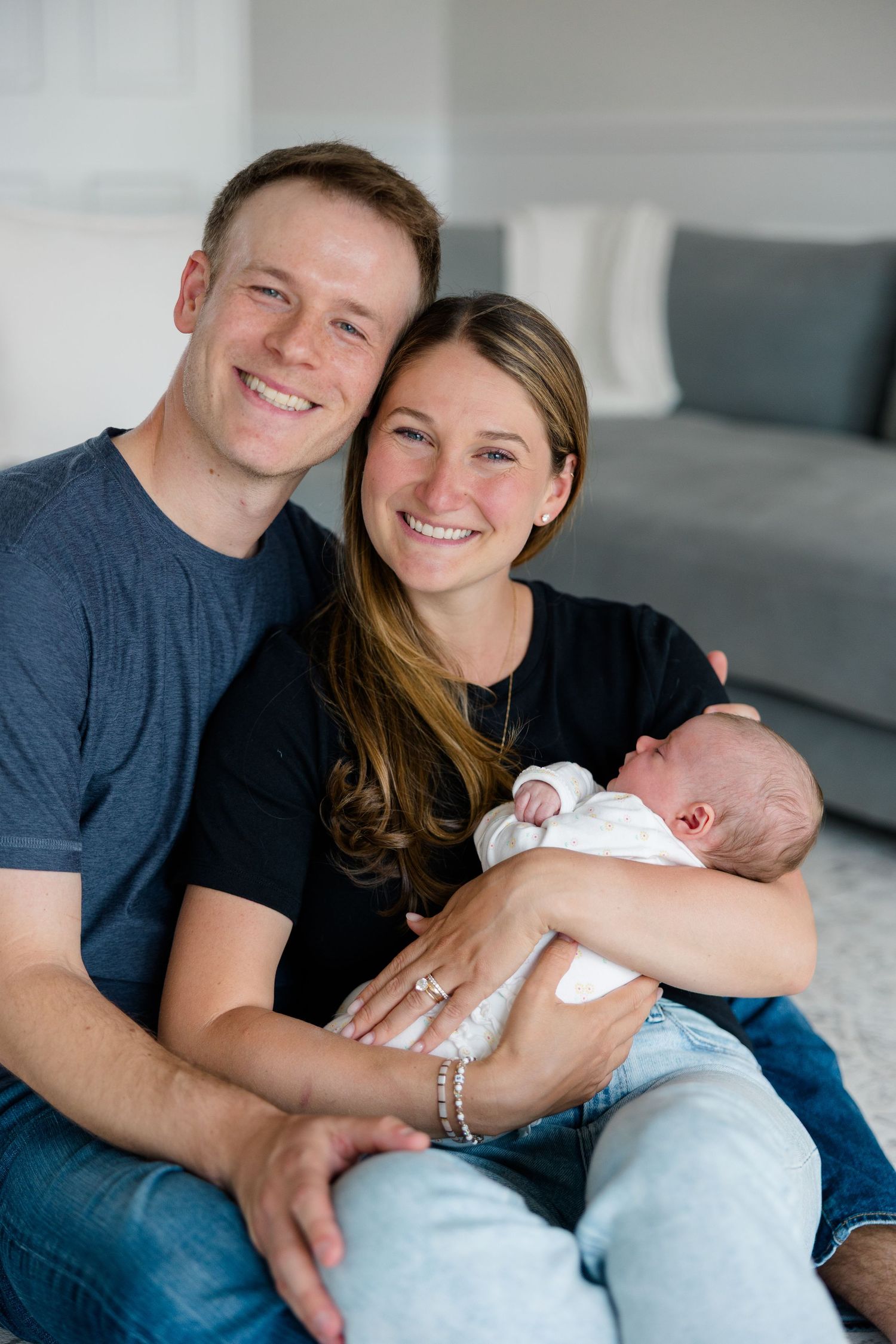 A series of tender moments captured between a couple and their newborn baby on a light colored couch.