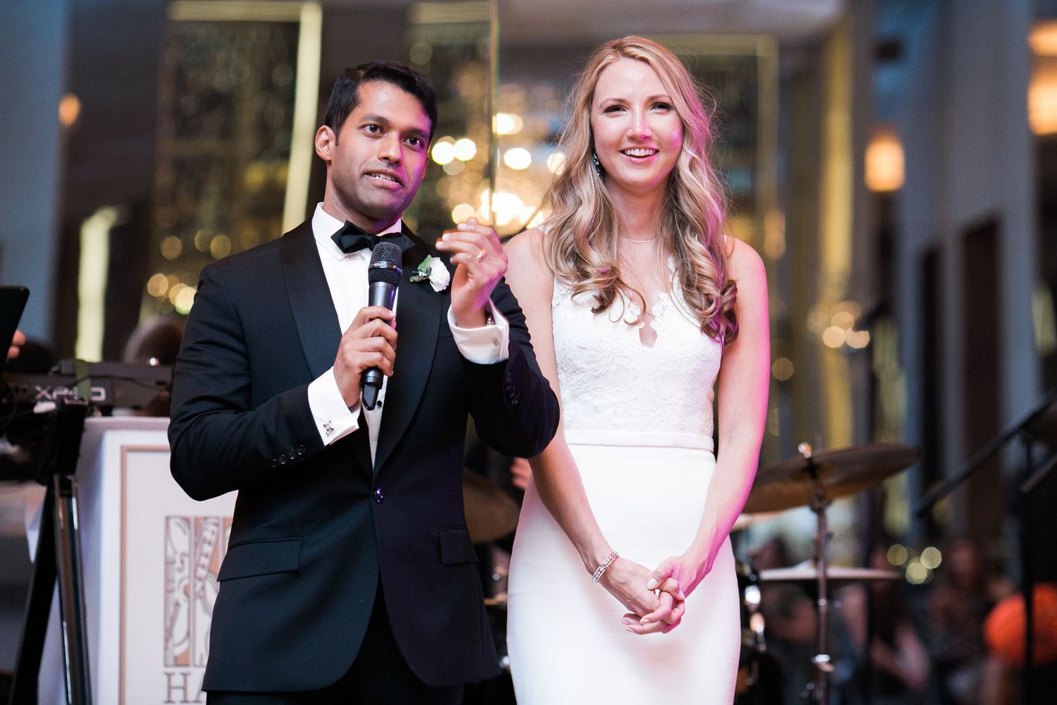 A formal event speech at an elegant venue with decorative lighting in the background.