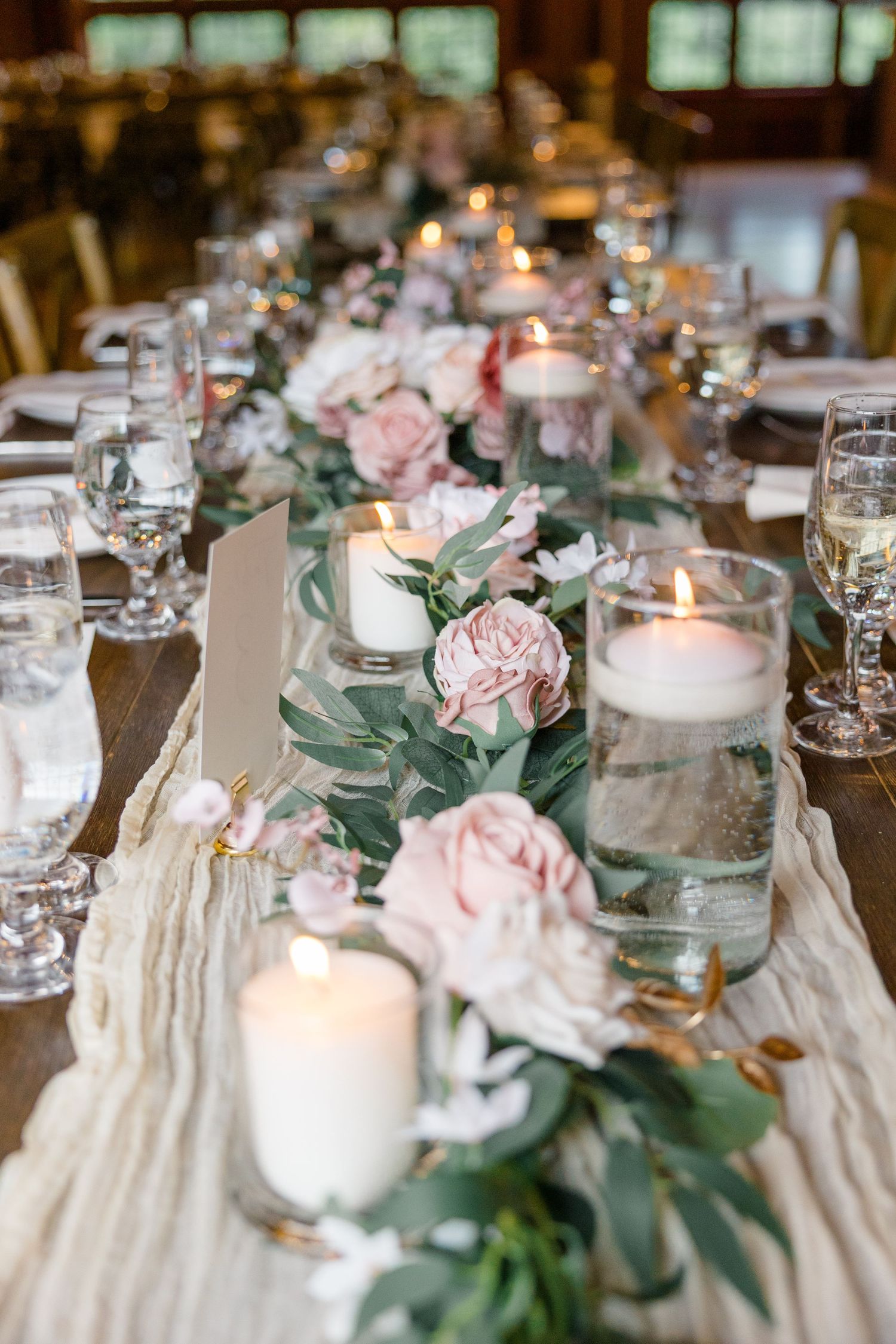 Elegant wedding table setting with blush roses, eucalyptus, and flickering candles.