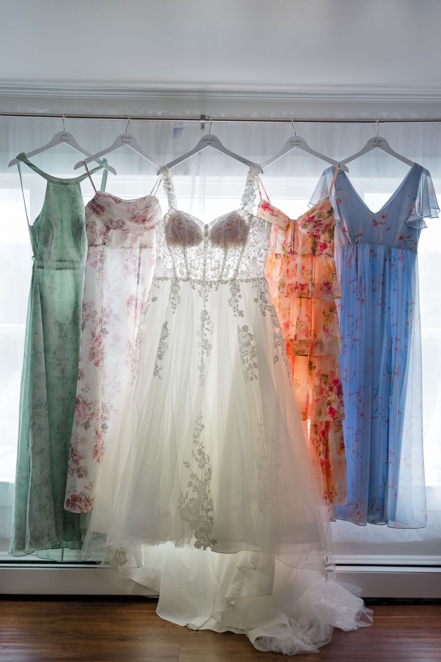 Beautiful bridesmaid dresses in orange, blue, white and green hanging on display.