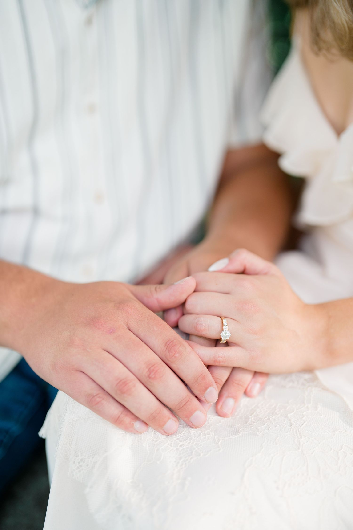 Close-up of couple holding hands showing a elegant diamond engagement ring on brides finger.