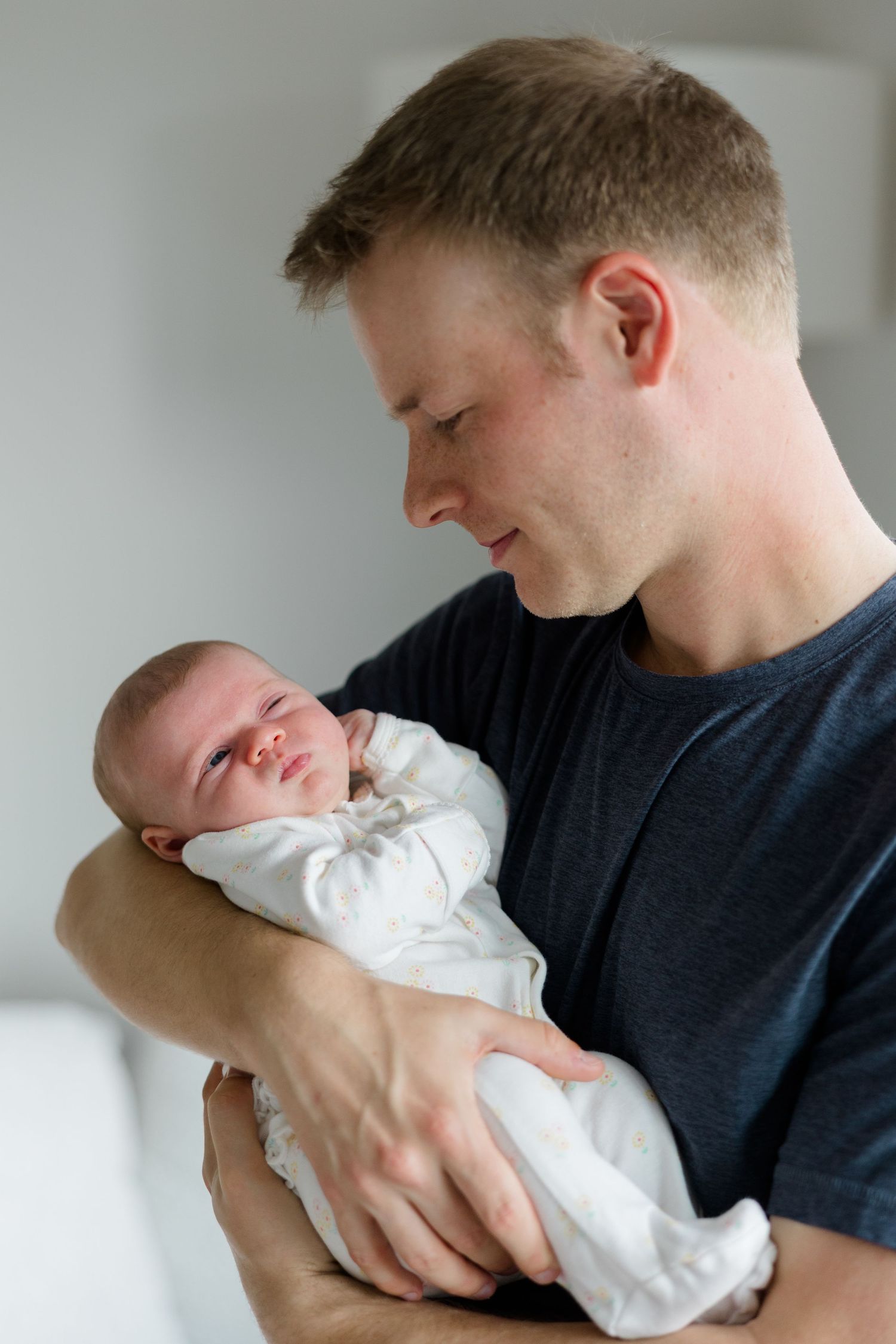 A series of intimate shots showing a parent cradling their swaddled newborn baby.