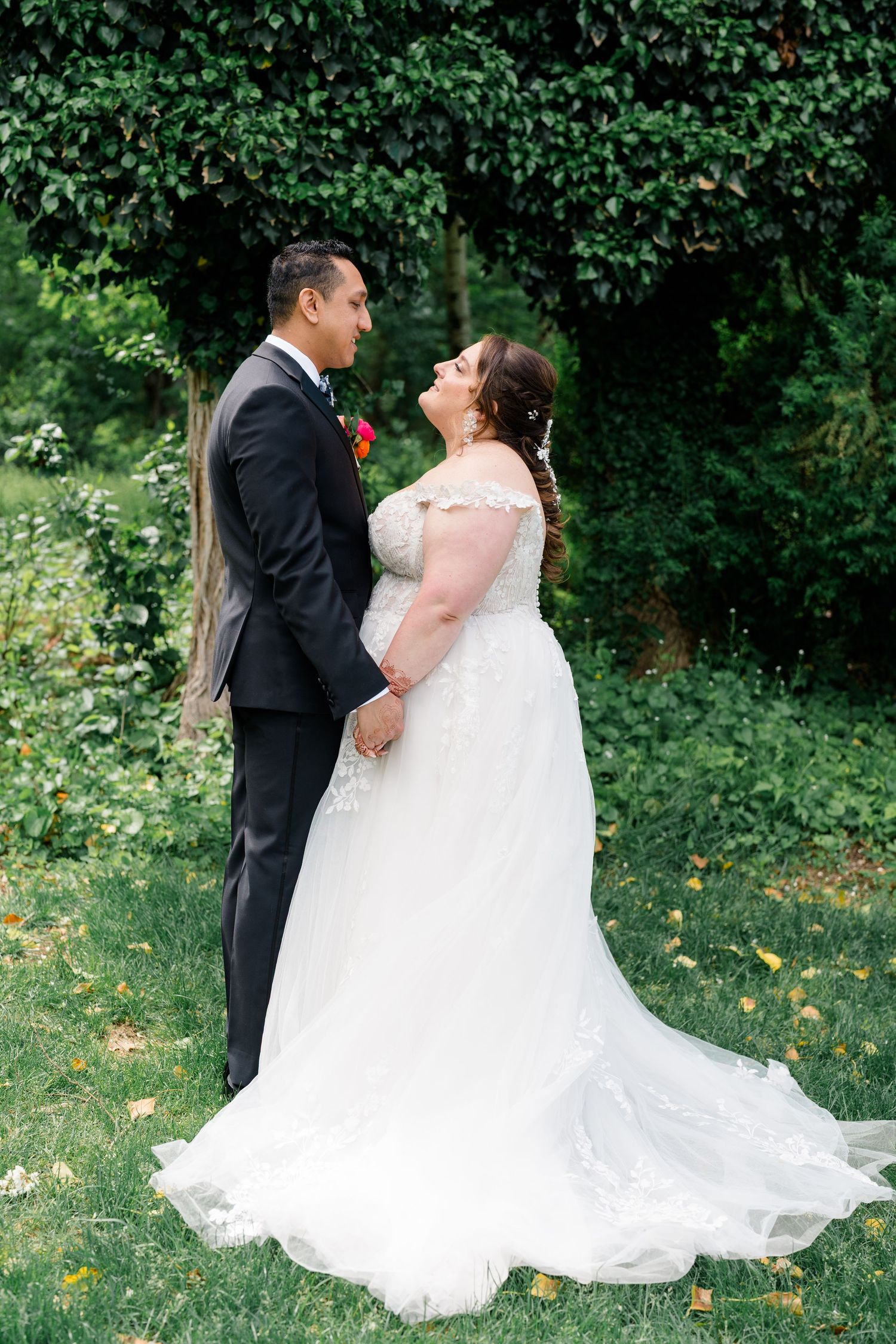 A wedding couple shares a romantic moment together in a lush garden setting with greenery in the background.