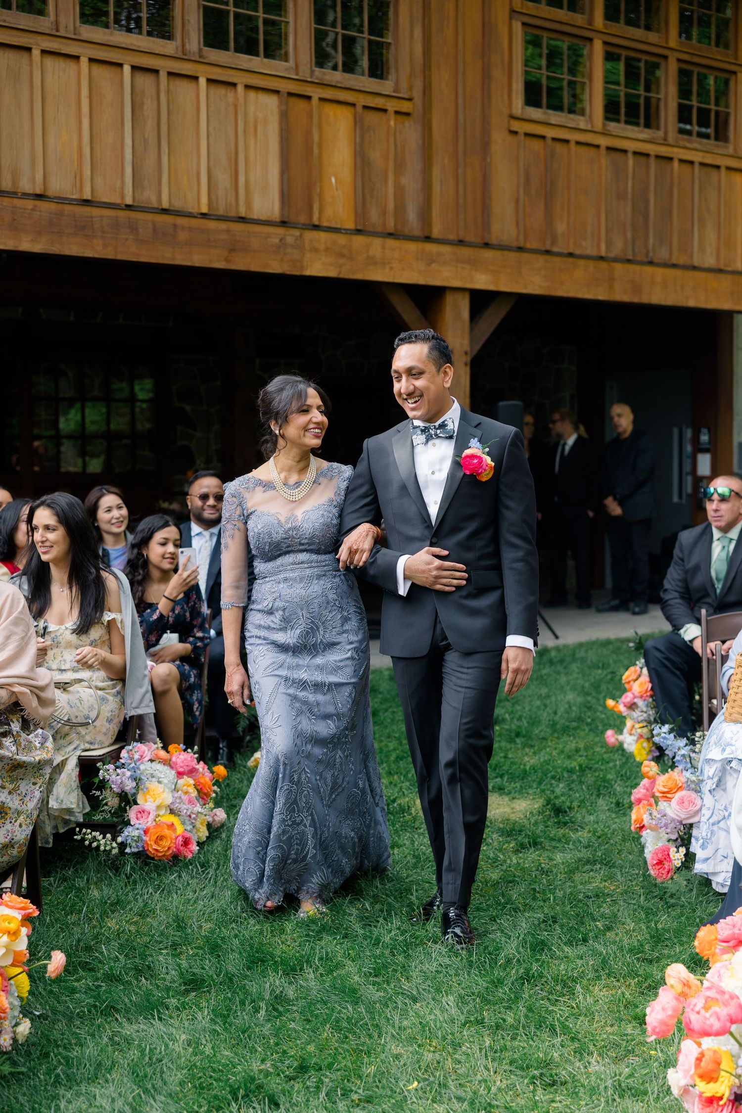 Formal procession during outdoor wedding ceremony at rustic wooden venue.