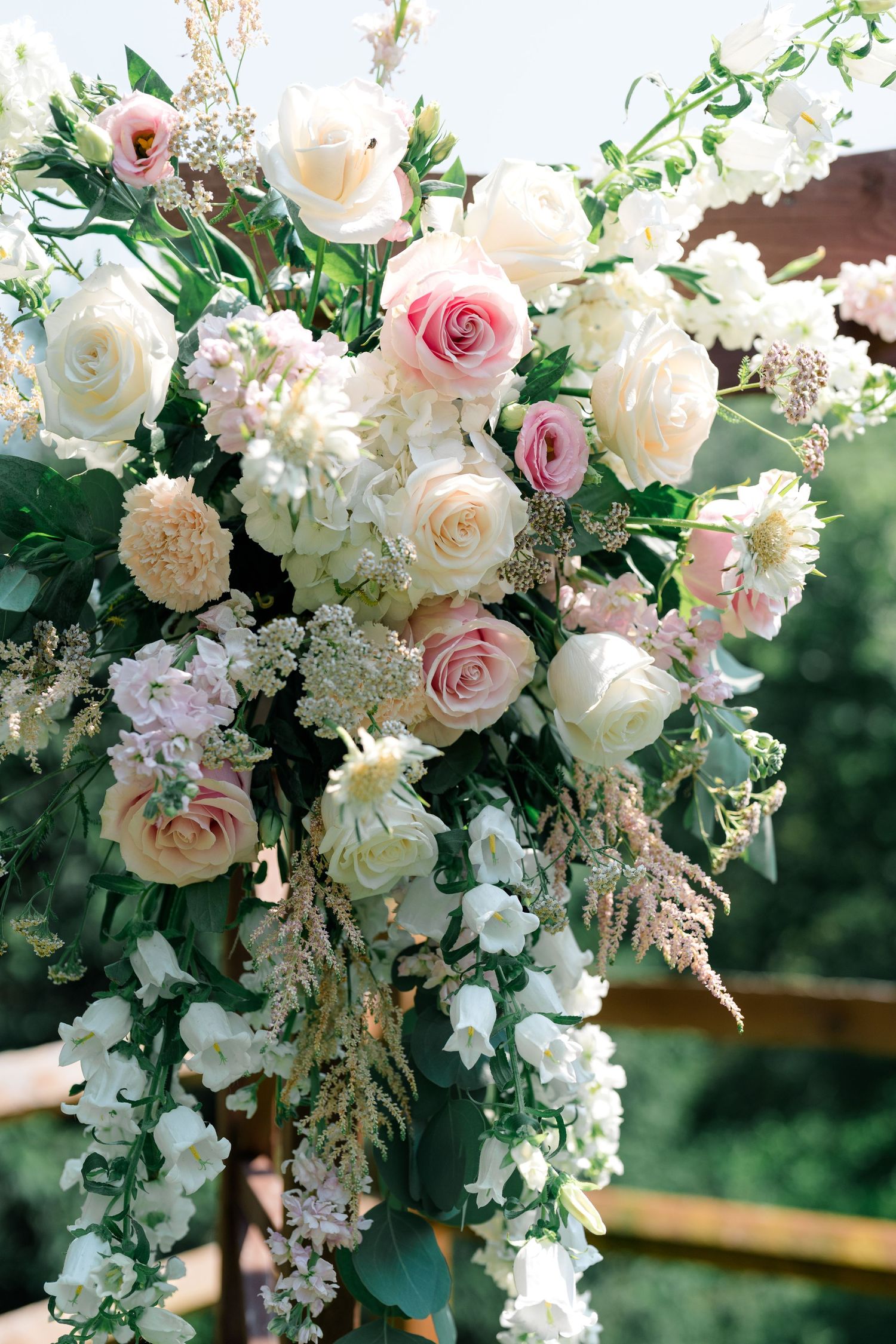 Elegant floral arch arrangement with white and pink roses and greenery.