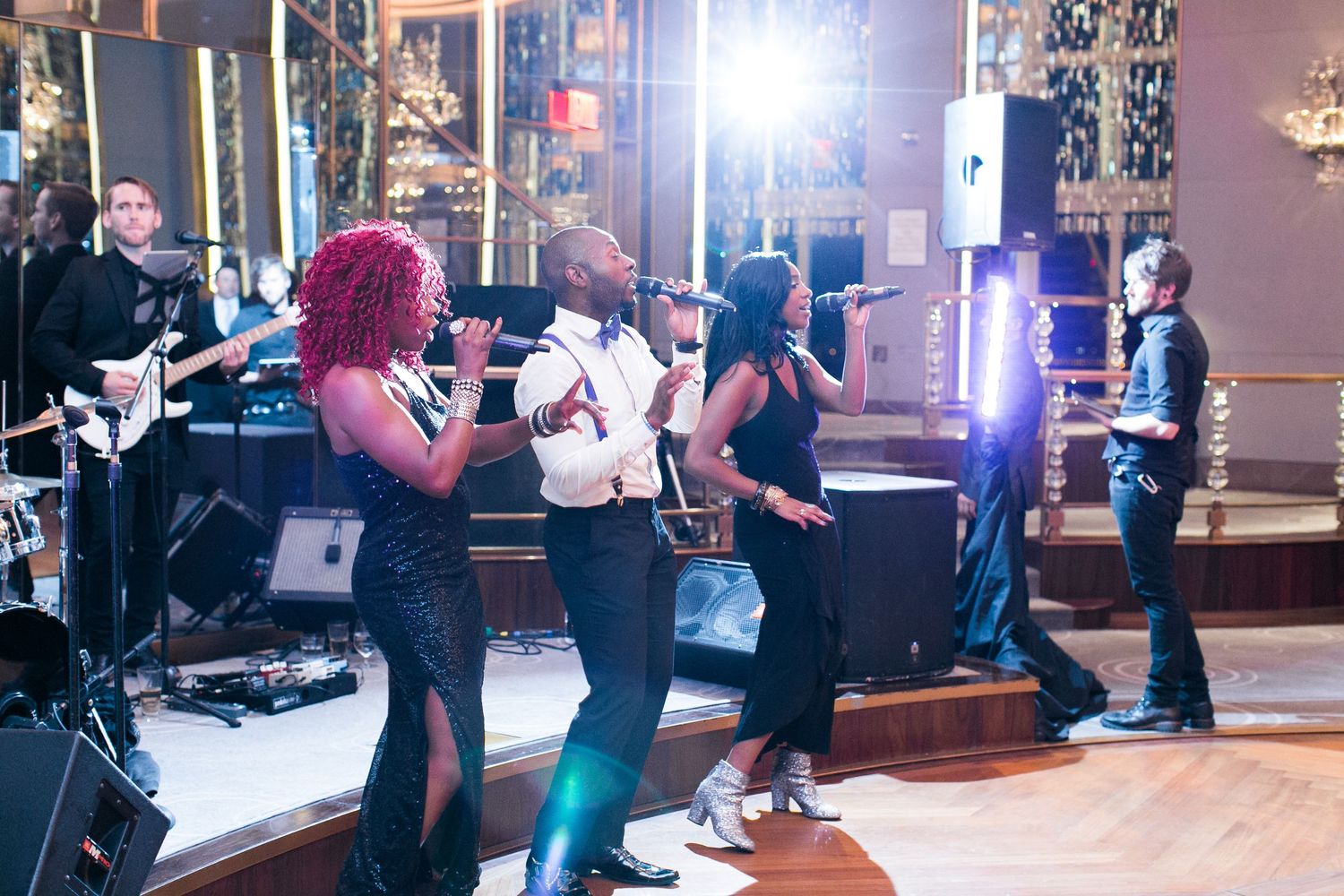Live band performs on stage at a reception with musicians and singers entertaining the crowd.
