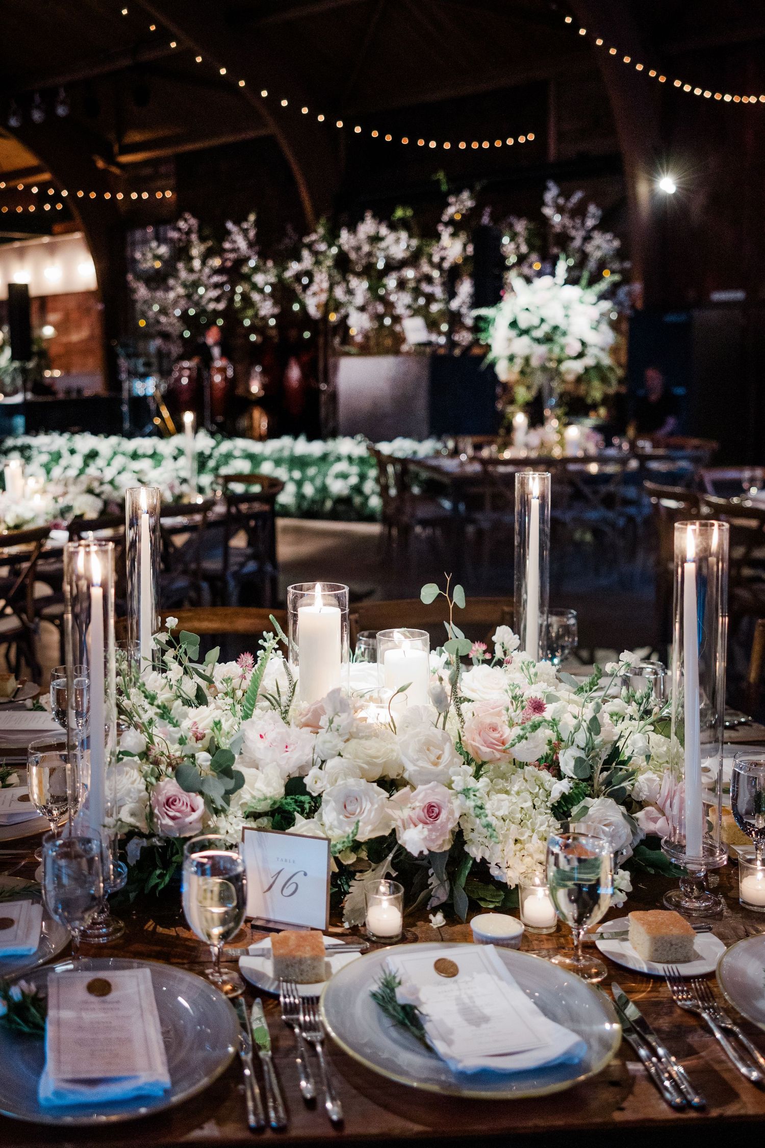 Elegant wedding table setting with white and pink floral centerpieces and crystal candle holders.