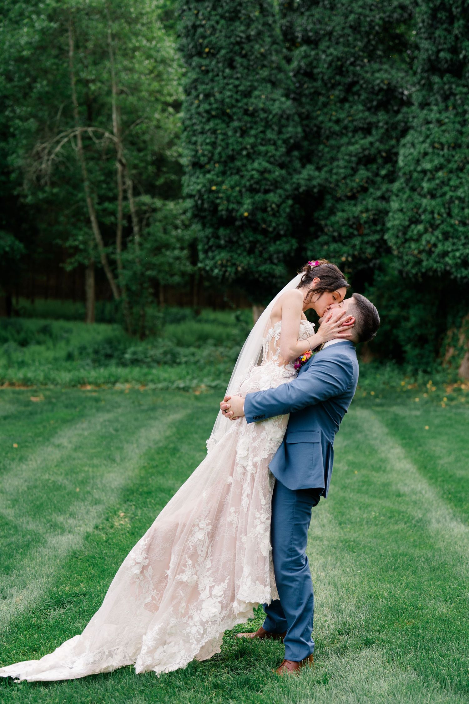 Romantic outdoor wedding portrait of couple embracing on manicured lawn.