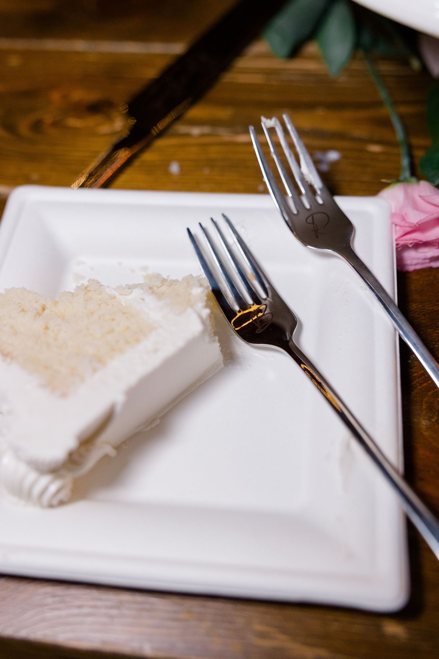 Place setting with white napkin and silverware on wooden table at wedding reception.